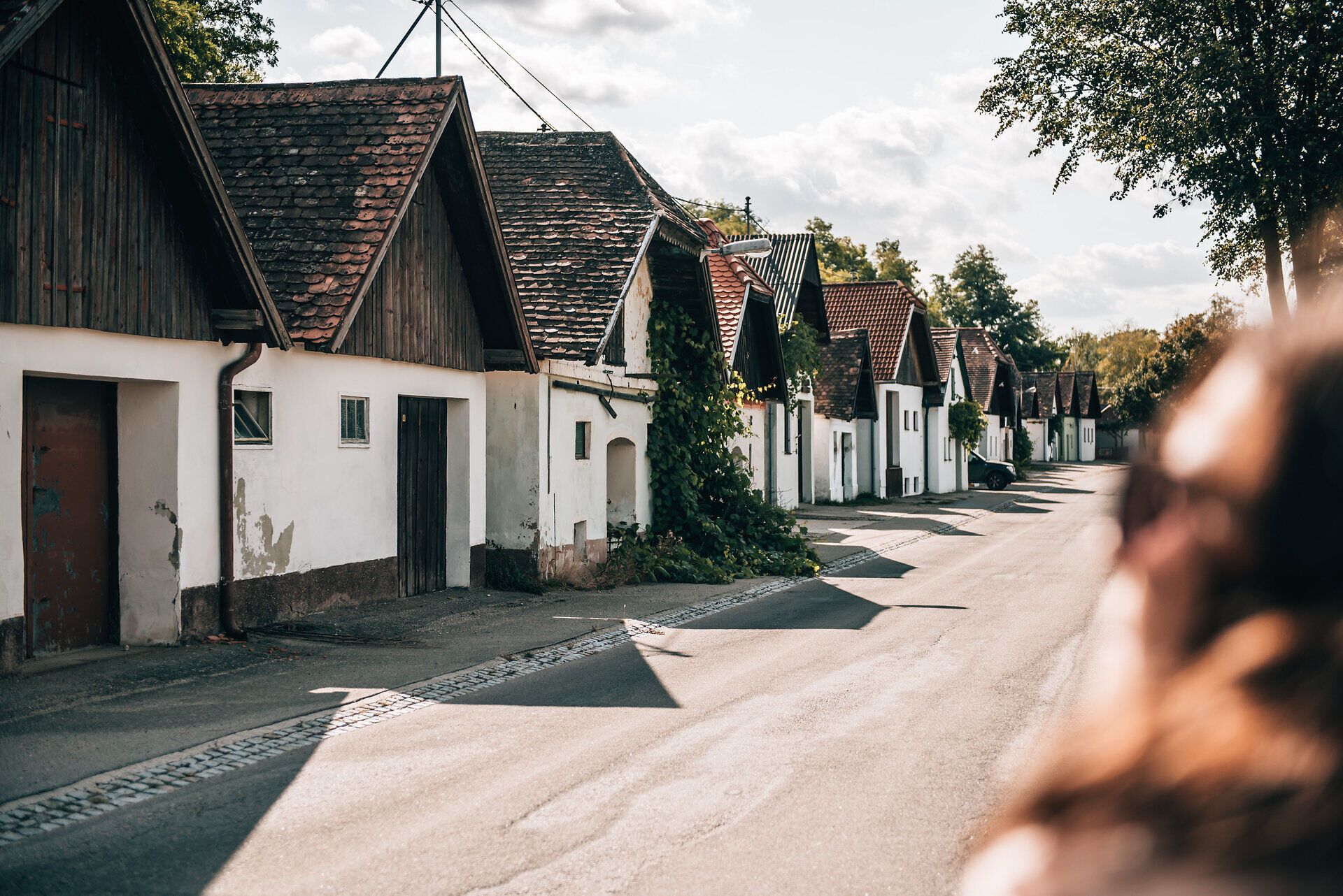 In der malerischen Kellergasse reihen sich charmante Weinhäuser aneinander, umgeben von bunten Herbstblättern. Die sanfte Sonne taucht die Szenerie in warmes Licht und lädt dazu ein, die köstlichen Weine der Region zu probieren. Ein Ort, der die Sinne verzaubert und die Seele beruhigt.