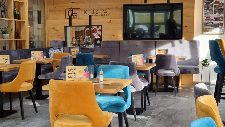 Pohled do interi&eacute;ru modern&iacute; kav&aacute;rny s barevn&yacute;mi sametov&yacute;mi židlemi a dřevěn&yacute;mi stěnami.