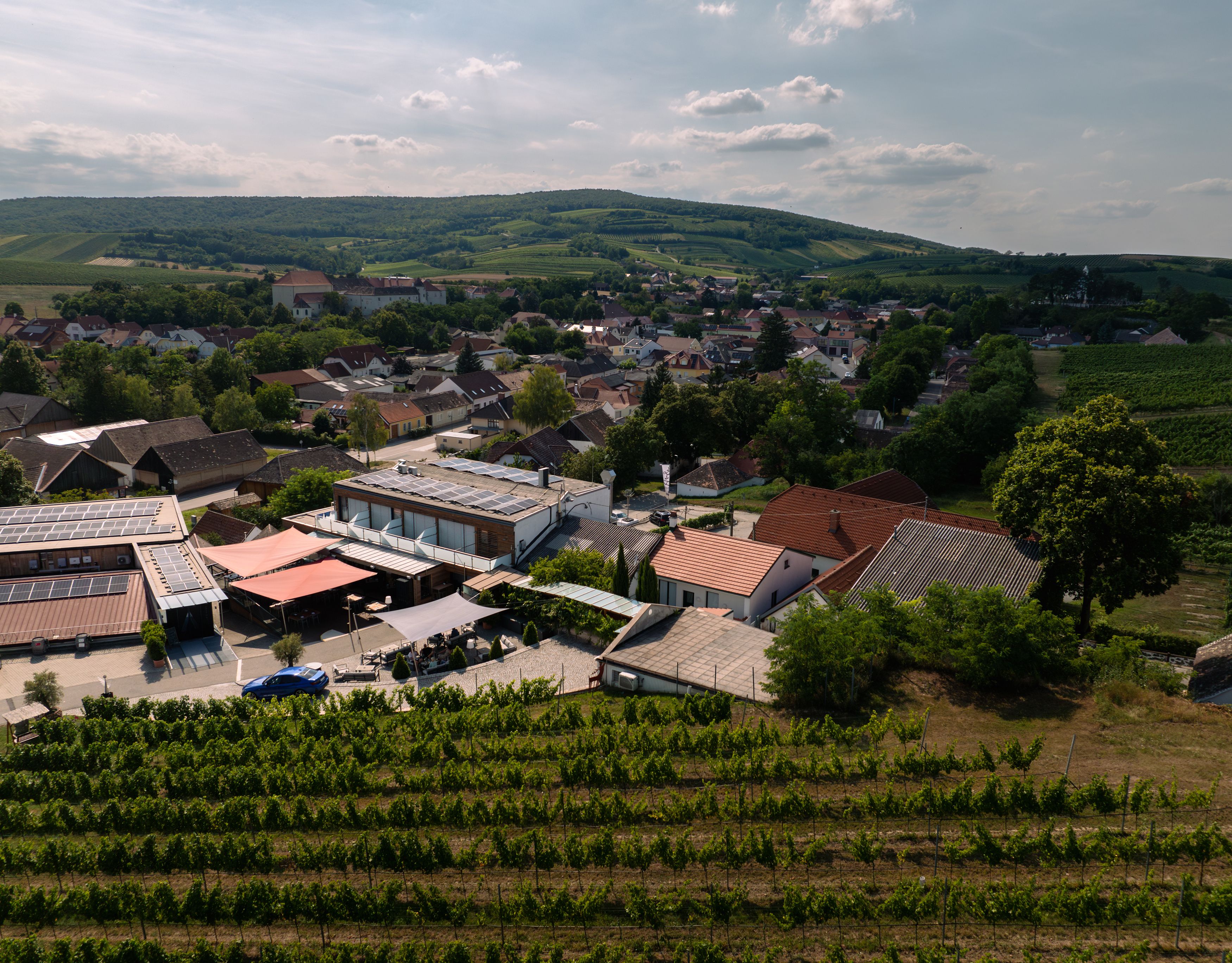 Letecký pohled na vinařství s okolními budovami a vinicemi.