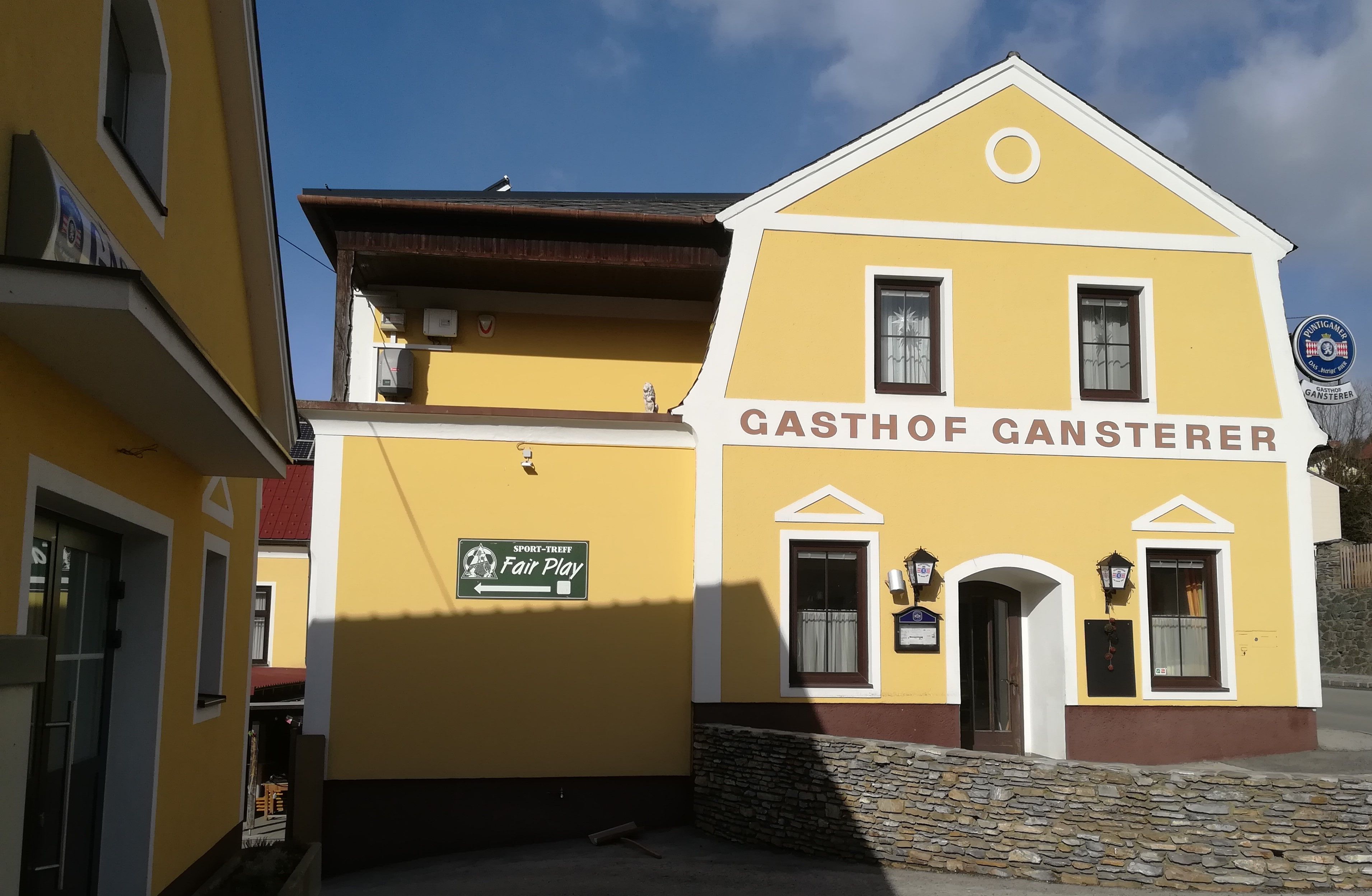 Žlutá budova s nápisem "Gasthof Gansterer".