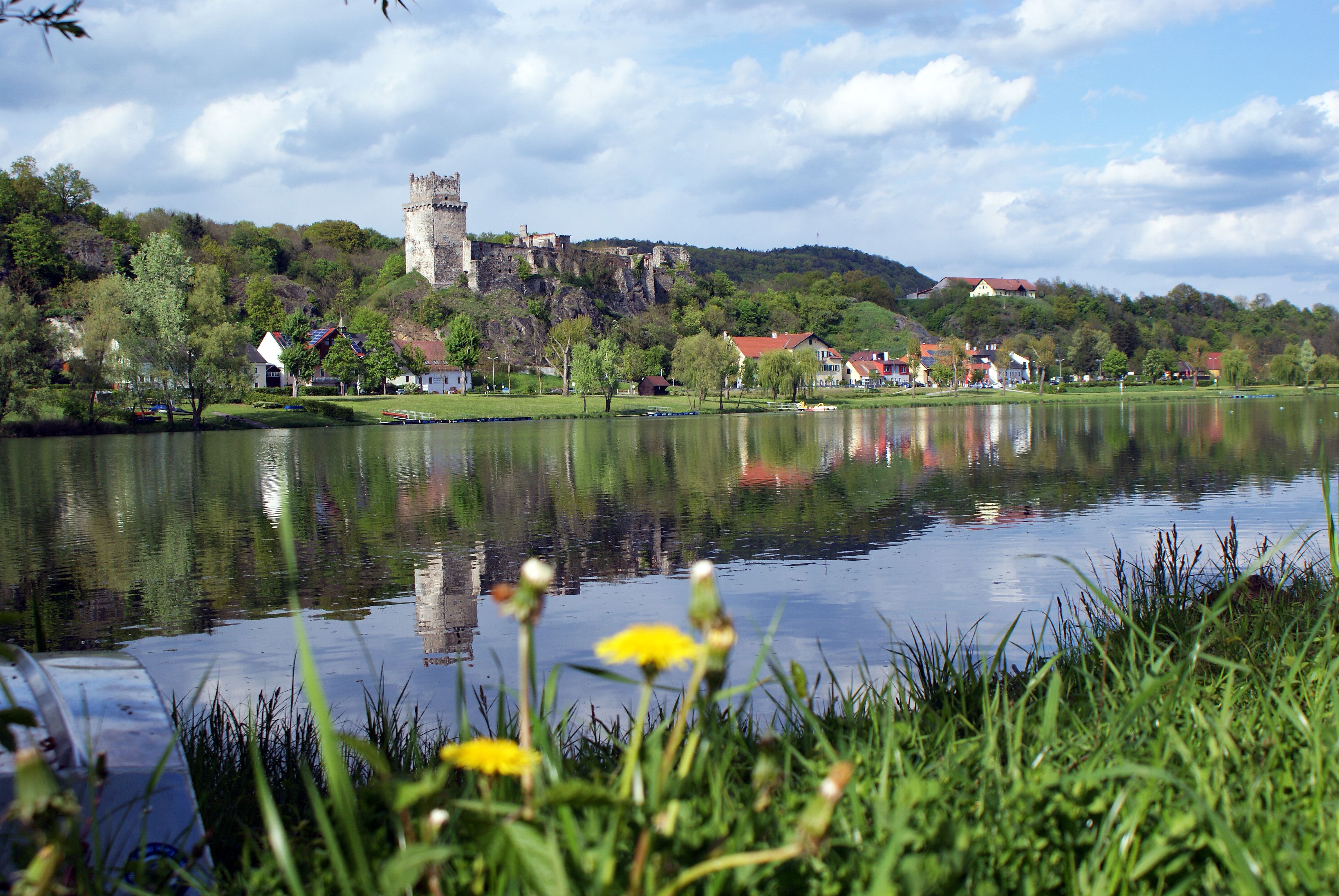 Hrad Weitenegg a vesnice na břehu řeky s odrazem ve vodě.