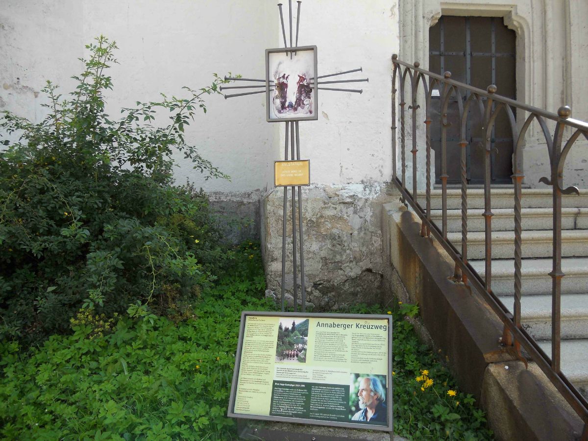 Cedule s informacemi o křížové cestě v Annabergu vedle schodiště a rostlin.