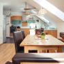 Modern&iacute; kuchyně s dřevěn&yacute;m n&aacute;bytkem a j&iacute;deln&iacute;m stolem v bytě.