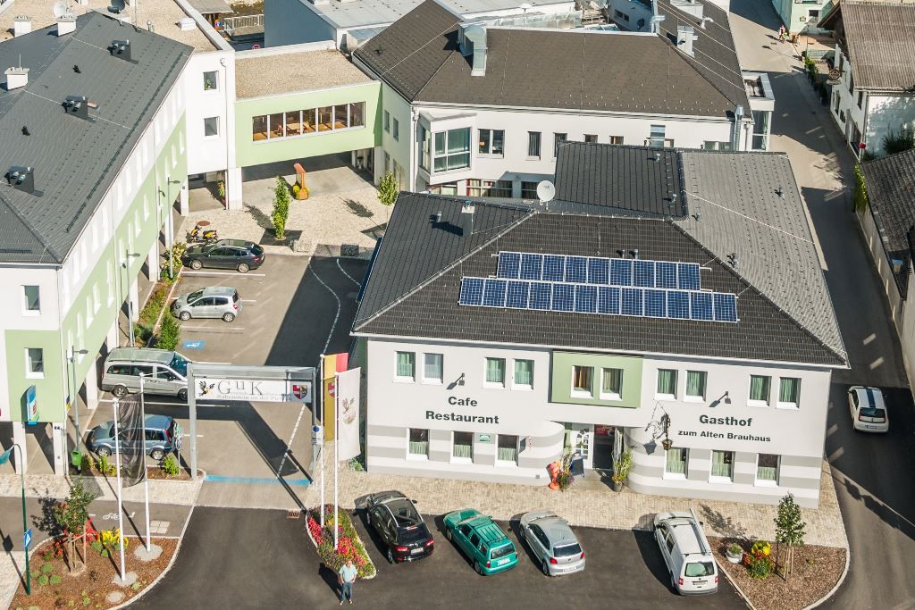 Letecký pohled na komplex budov s restaurací Gasthof zum Alten Brauhaus, solárními panely na střeše a několika zaparkovanými auty.