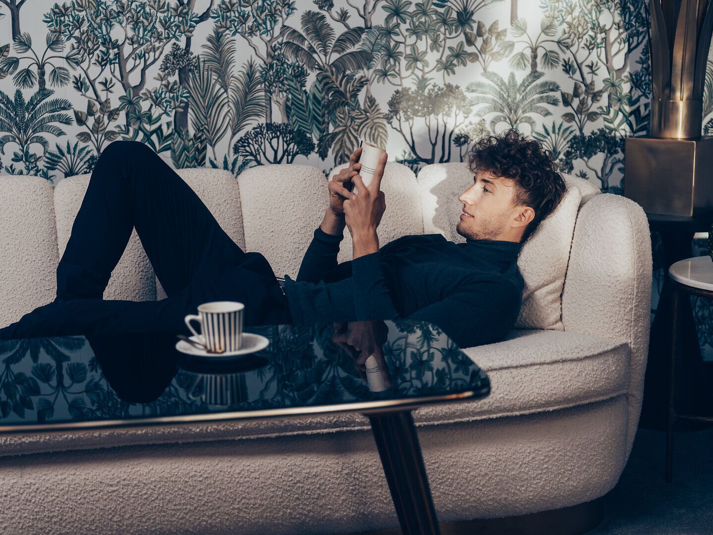 Inmitten der sanften Hügel der Wiener Alpen lädt eine gemütliche Couch zum Entspannen ein. Die üppige Pflanzenwelt im Hintergrund schafft eine harmonische Atmosphäre, während die sanften Lichtstrahlen den Raum erhellen. Hier kann man die Seele baumeln lassen und die Schönheit der Natur genießen.