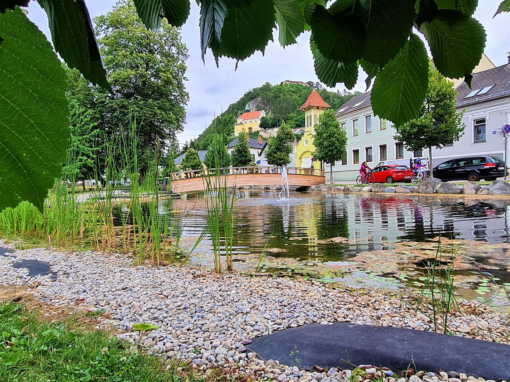 Pohled na horský kostel Pitten z parku s rybníkem a mostem