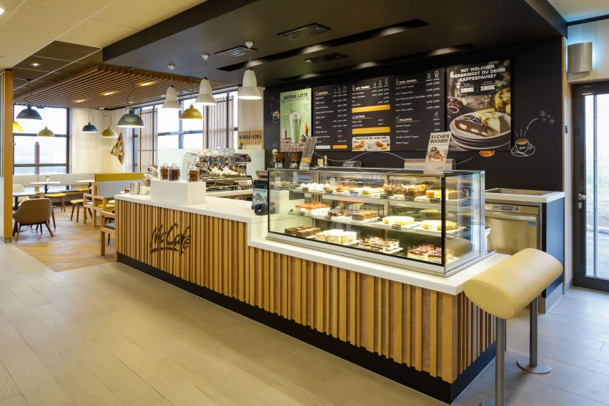 Pohled do interiéru kavárny McCafé s pultem a posezením.