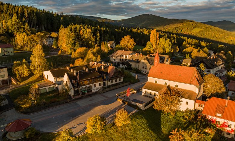 Letecký pohled na St. Corona am Wechsel s kostelem a okolními budovami v podzimní krajině.