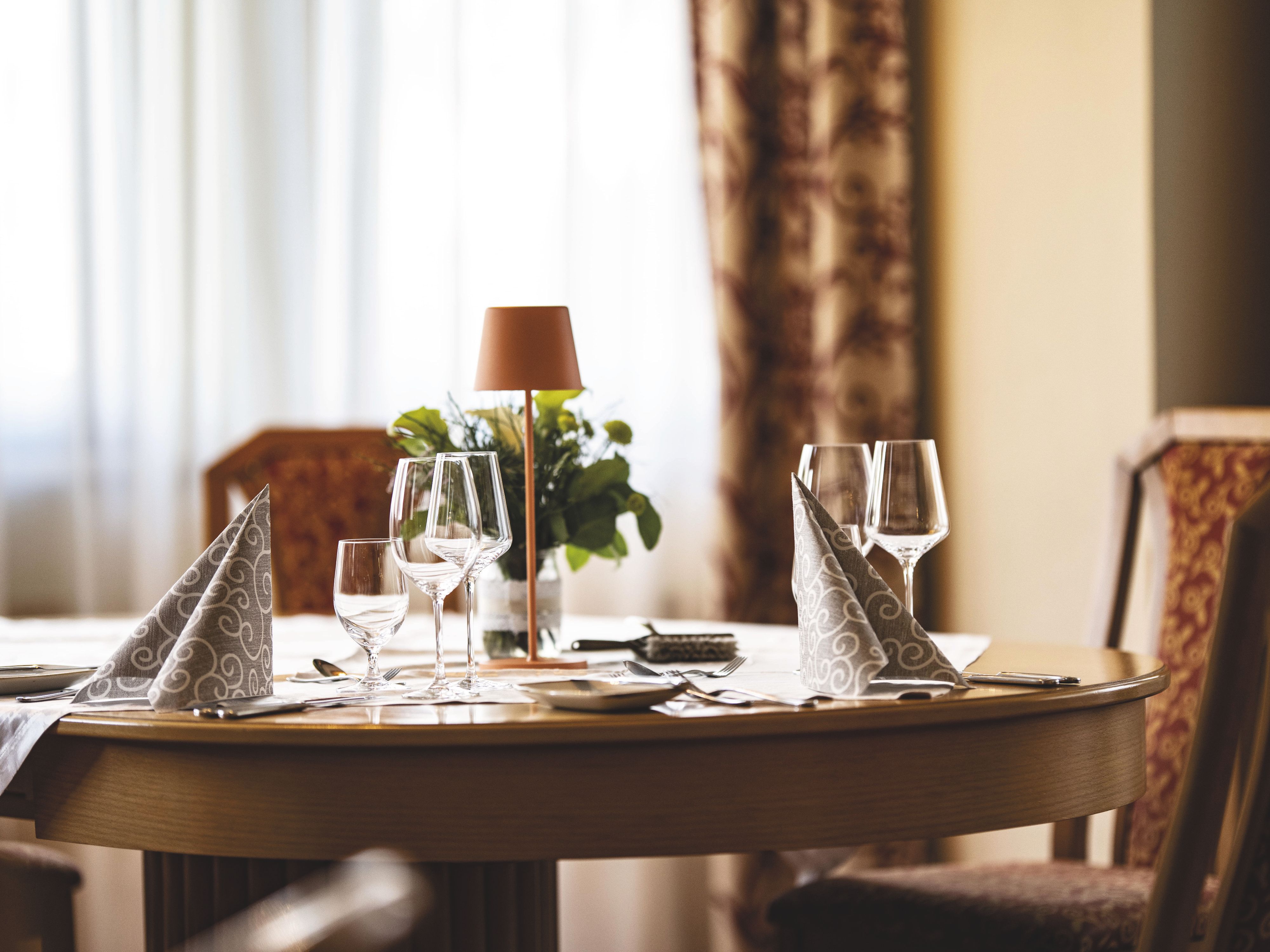 Elegantně prostřený stůl s sklenicemi na víno a ubrousky v restauraci.