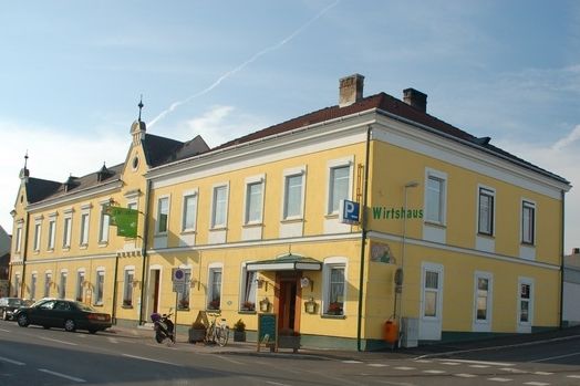 Žlutá hospoda na rohu ulice s několika okny a vchodem.