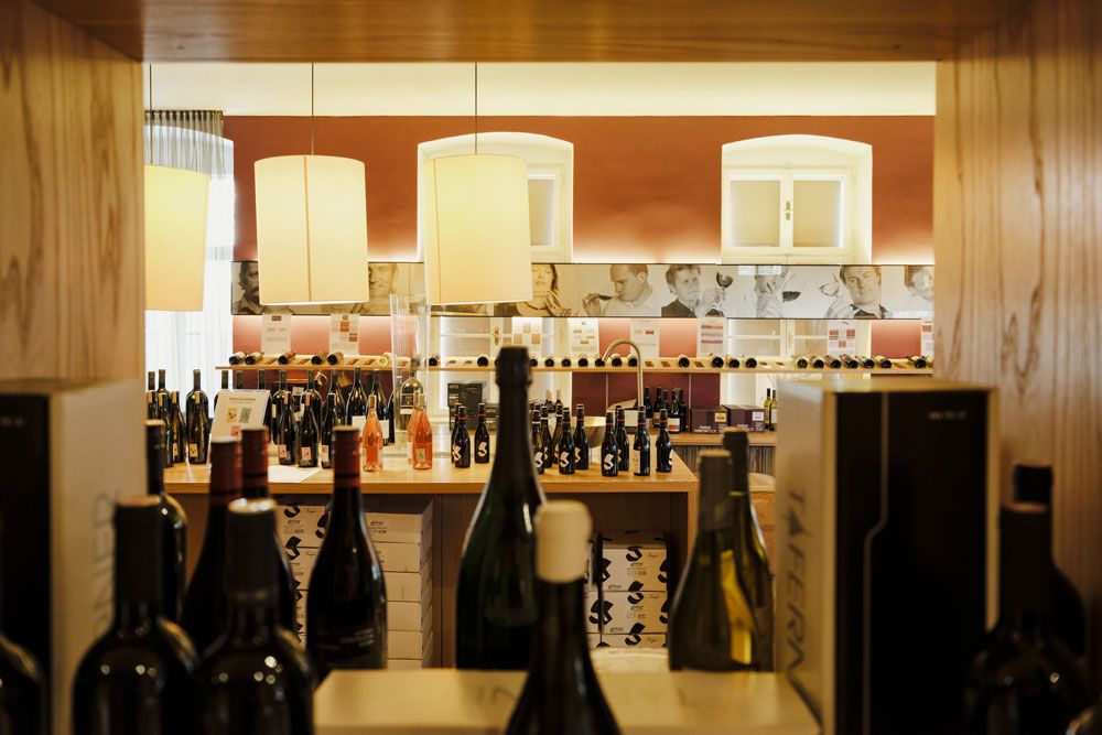 Pohled do interiéru vinotéky s lahvemi vína a ozdobnými lampami.
