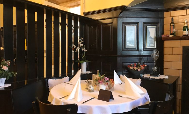 Útulný stůl v tradiční restauraci s tmavým dřevěným obložením a dekorativními květinami.