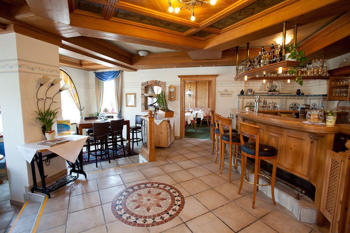 Útulný hotelový bar s dřevěným nábytkem a dekorativní dlažbou.