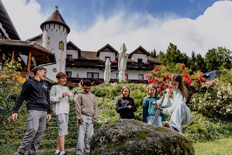 Děti si hrají s mečem v kameni před hotelem.