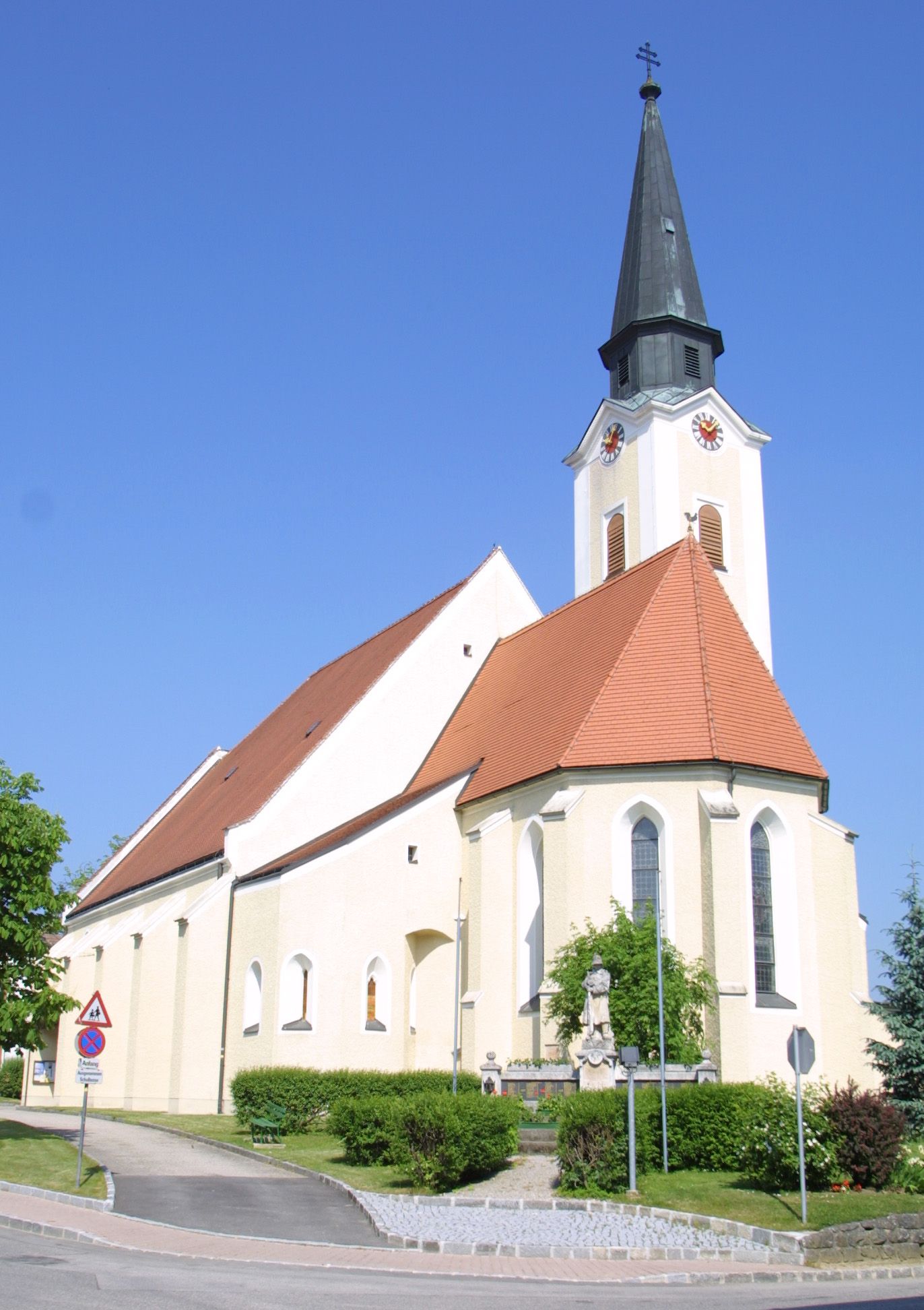 Kostel v Hürmu se špičatou věží a červenou střechou na pozadí modré oblohy.