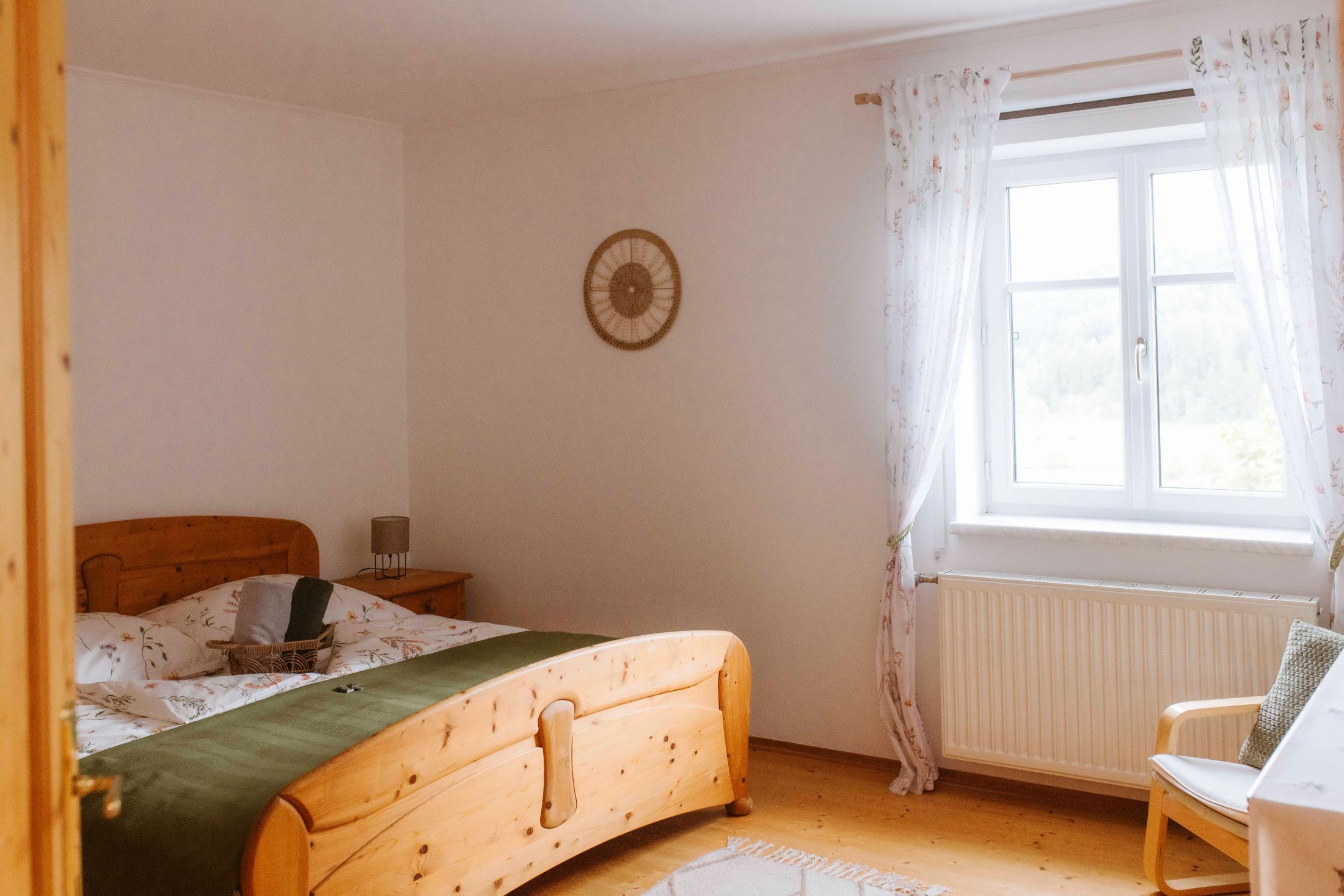 Útulný dvoulůžkový pokoj s dřevěným nábytkem a oknem se závěsy.