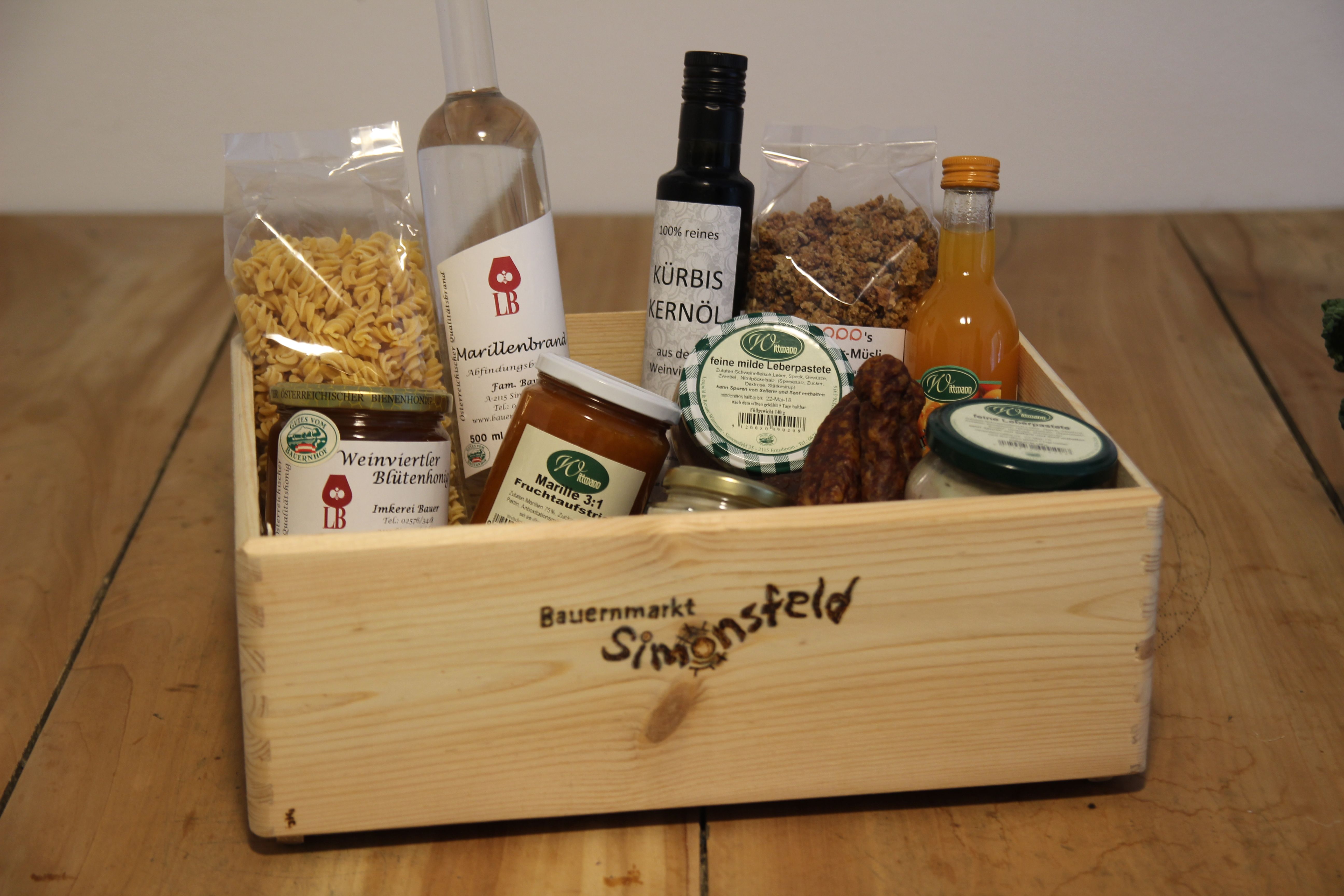 Dřevěná krabička s regionálními produkty, jako je olej, med, džem a těstoviny.