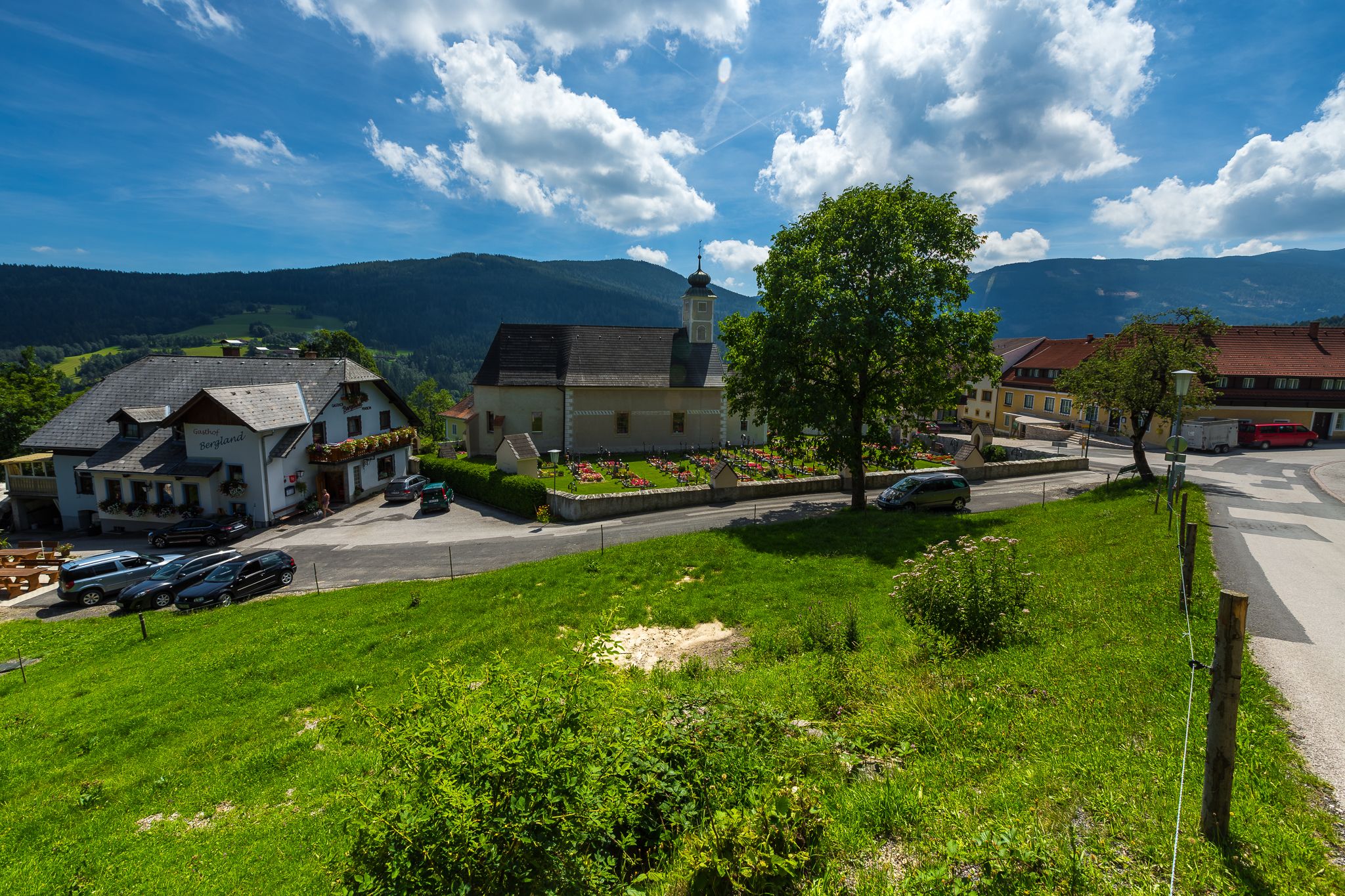 Venkovská scéna s kostelem, hostincem a zelenou loukou v Aspangbergu-Sv. Petru.
