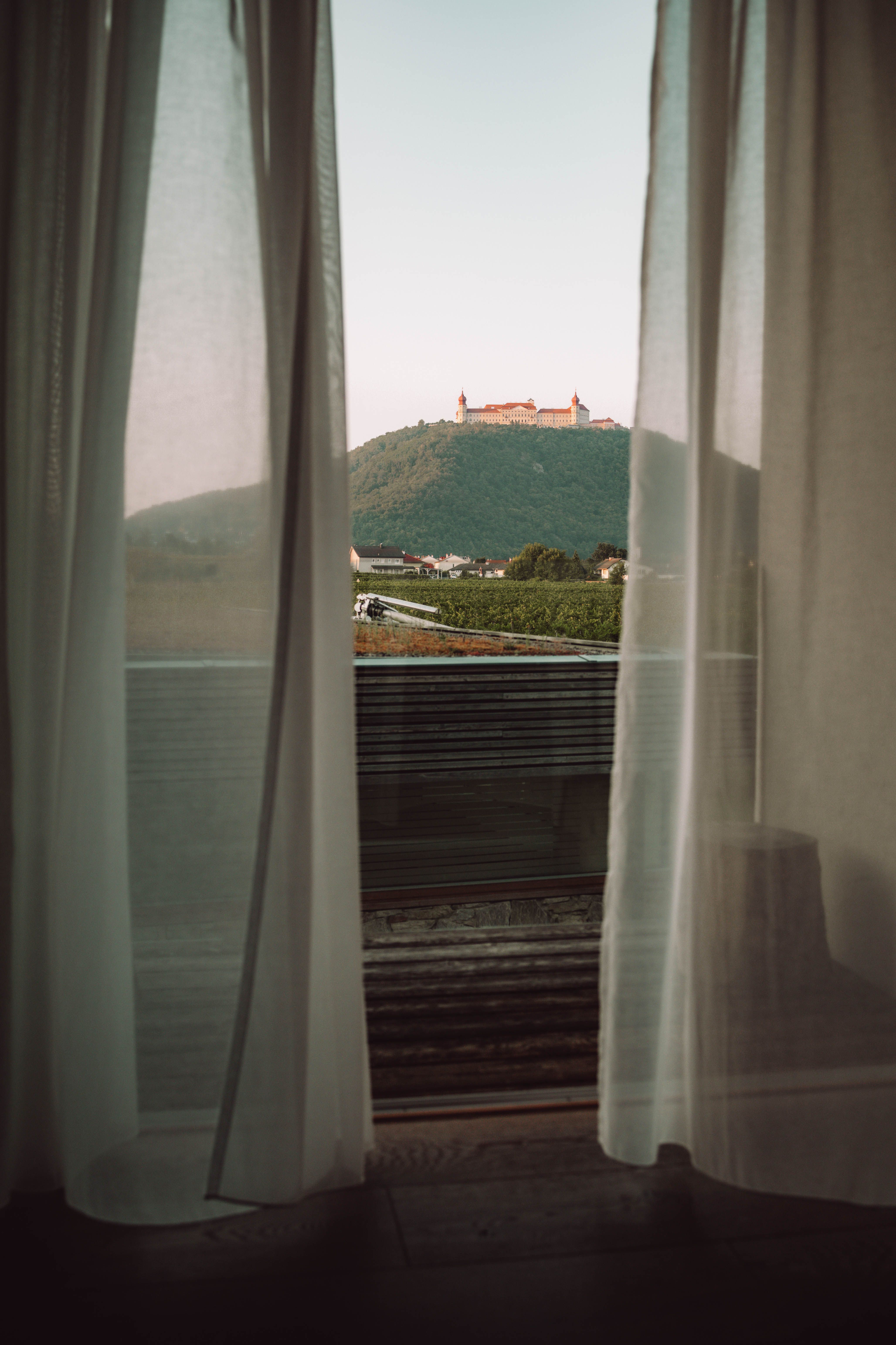 Vnější pohled na vinařství a hotel MALAT s moderní architekturou a vozidlem v popředí.