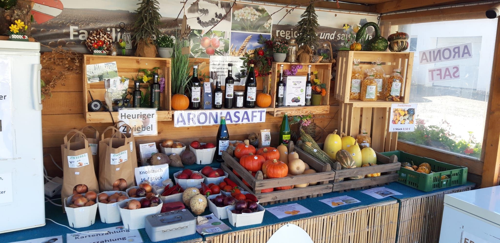Stánek s regionálními produkty, jako jsou dýně, cibule a aroniový džus.