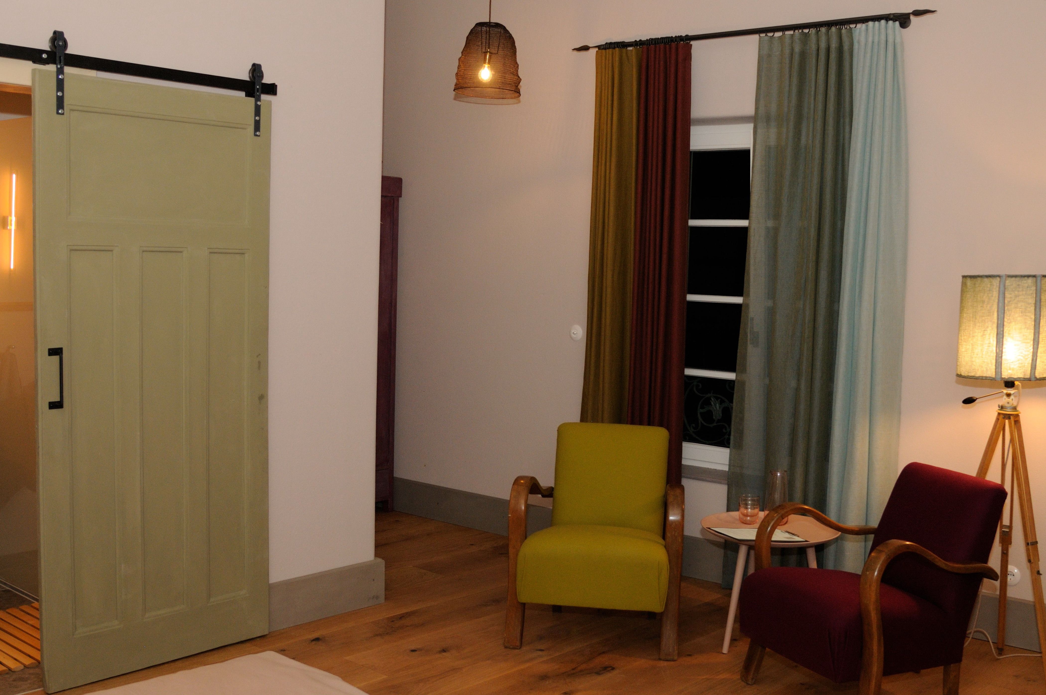 Útulný pokoj se dvěma křesly, závěsy a stojací lampou.