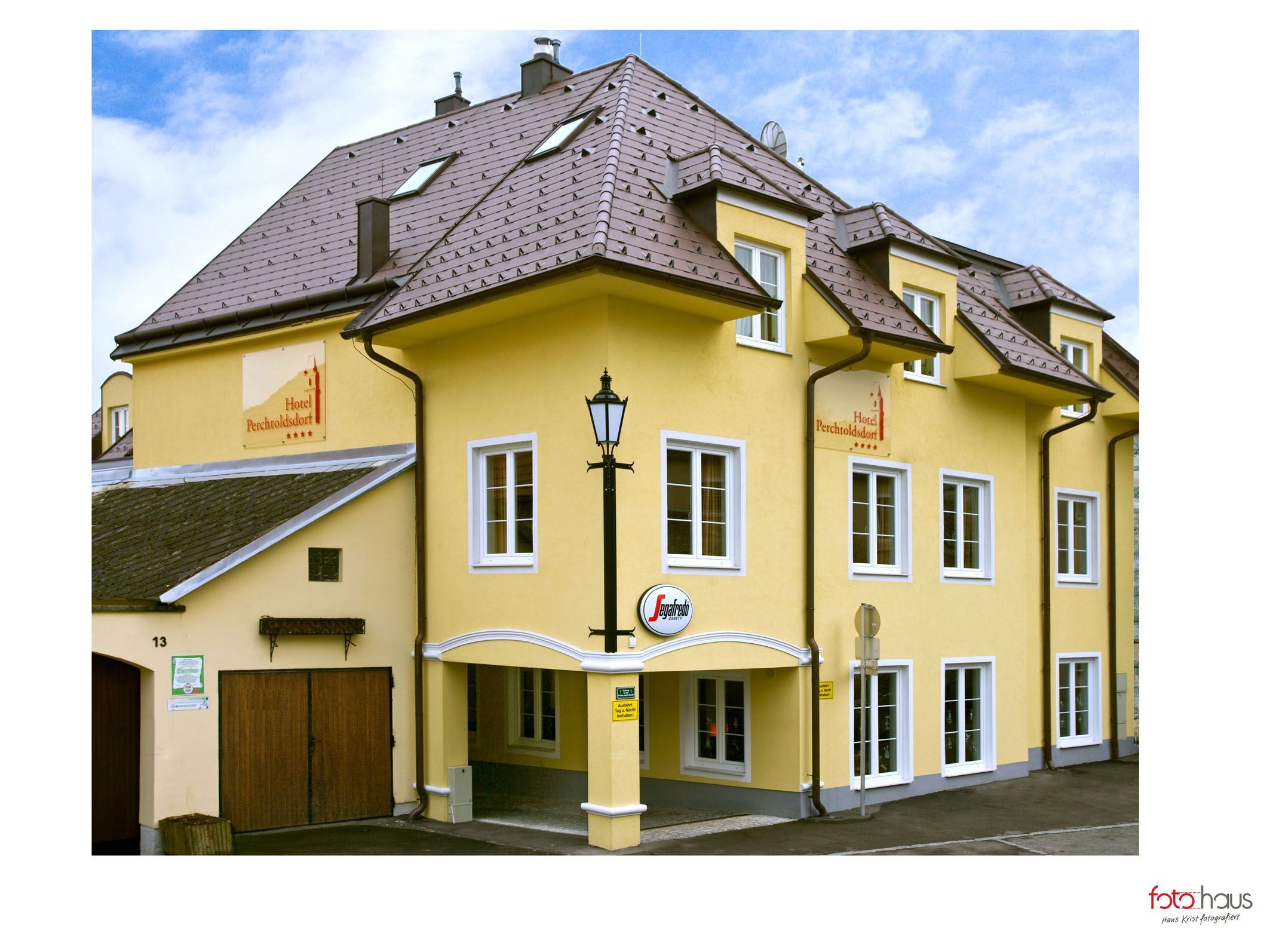 Žlutá hotelová budova s několika okny a nápisem "Hotel Perchtoldsdorf".