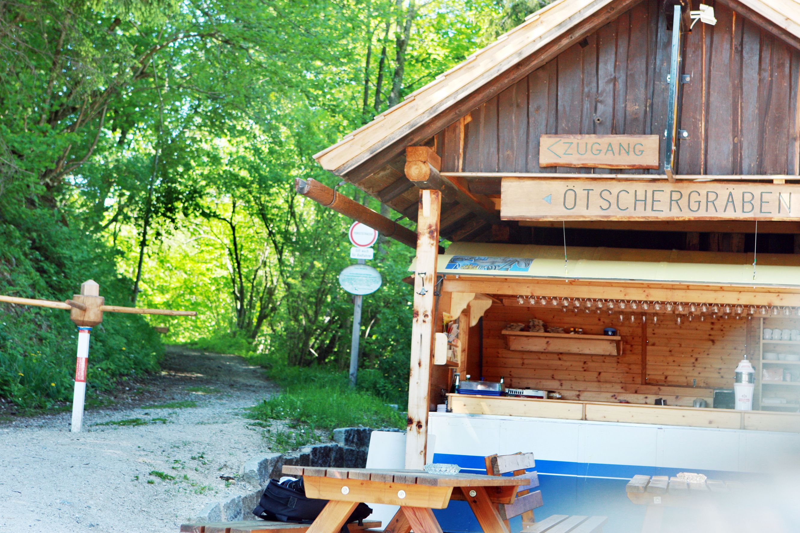 Dřevěná chata s nápisem "Ötschergräben" a lesní cestou v pozadí.