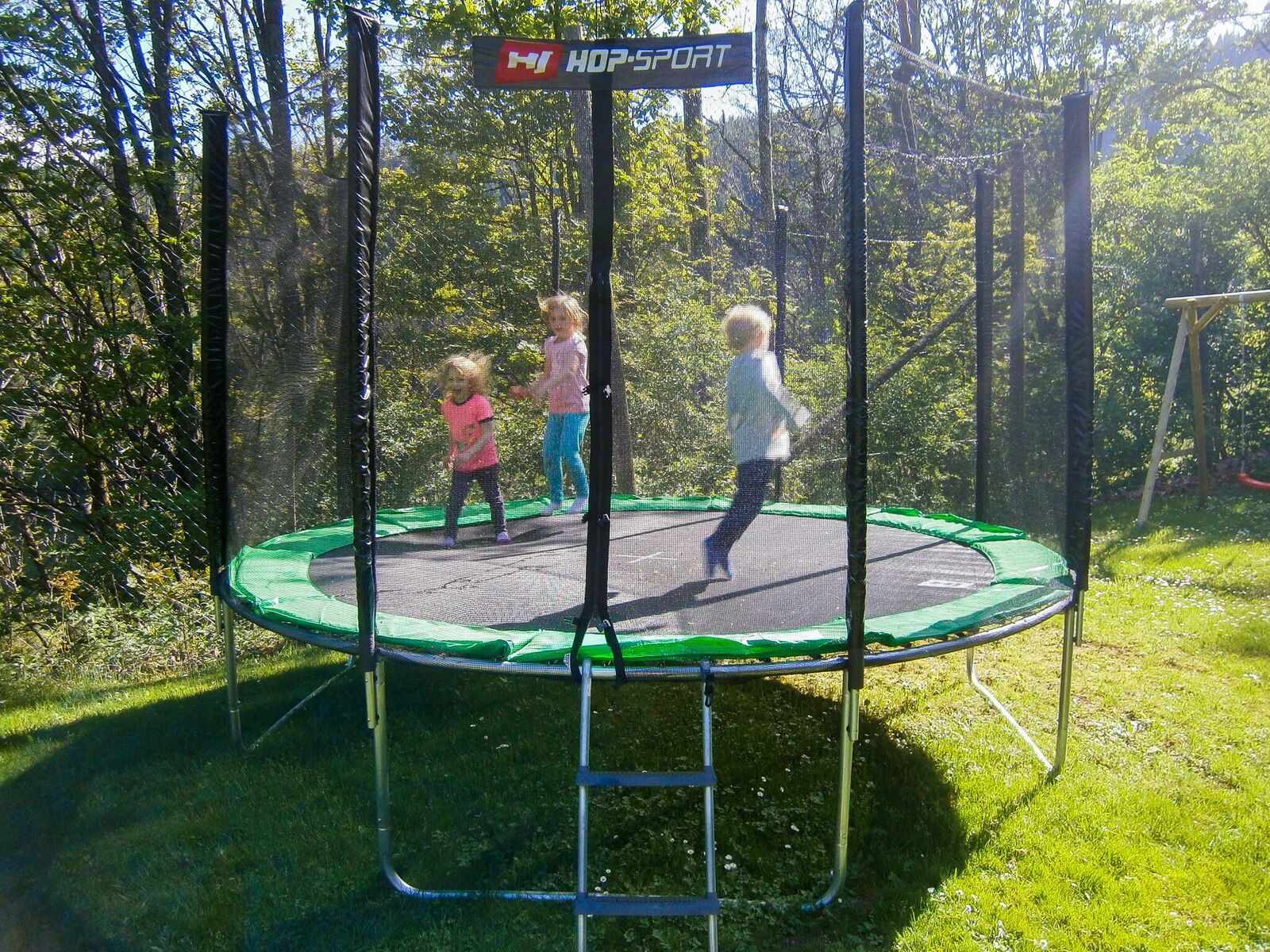 Tři děti skákající na trampolíně venku.
