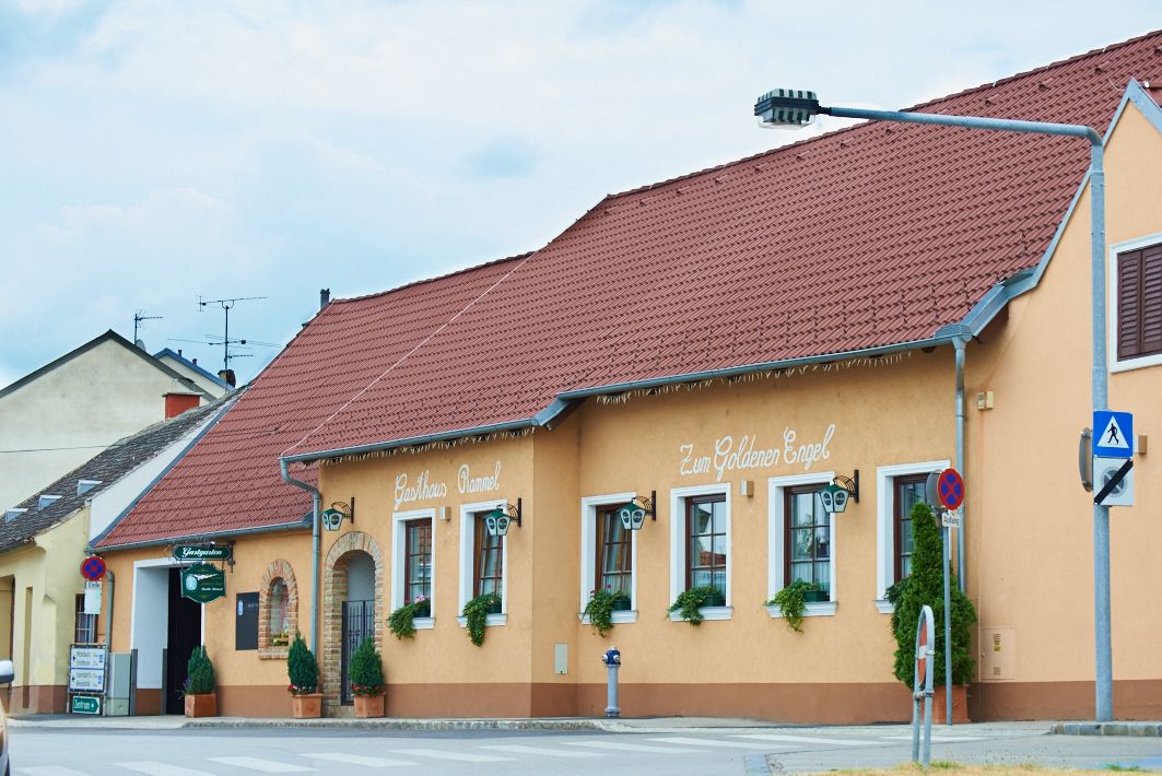 Tradiční hostinec se žlutou fasádou a červenou střechou s označením "Gasthaus Rammel" a "Zum Goldenen Engel".