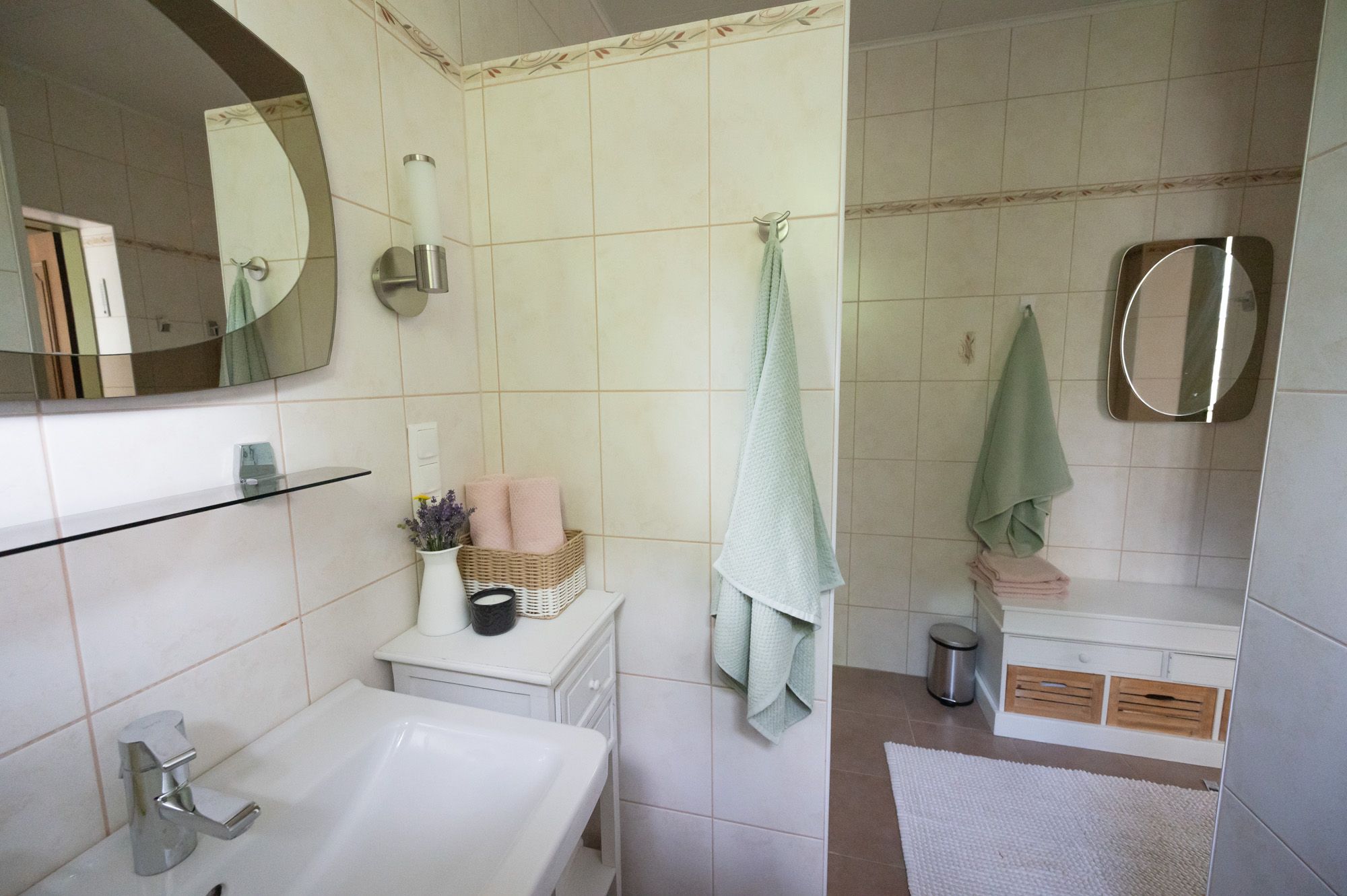 Moderní koupelna s umyvadlem, zrcadlem, ručníky a dekoracemi.