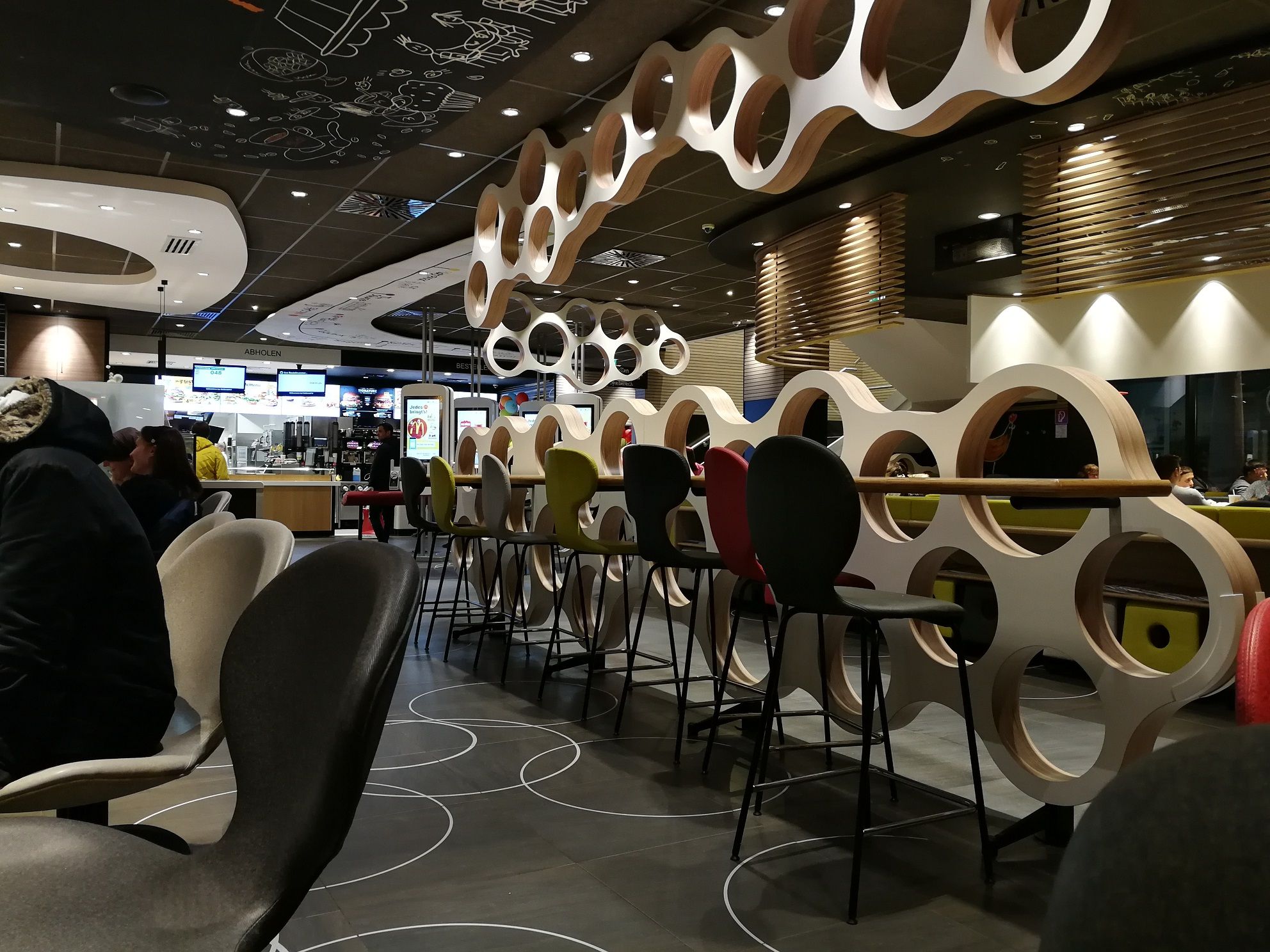 Pohled do interiéru restaurace McDonald's s moderním nábytkem a dekoracemi.