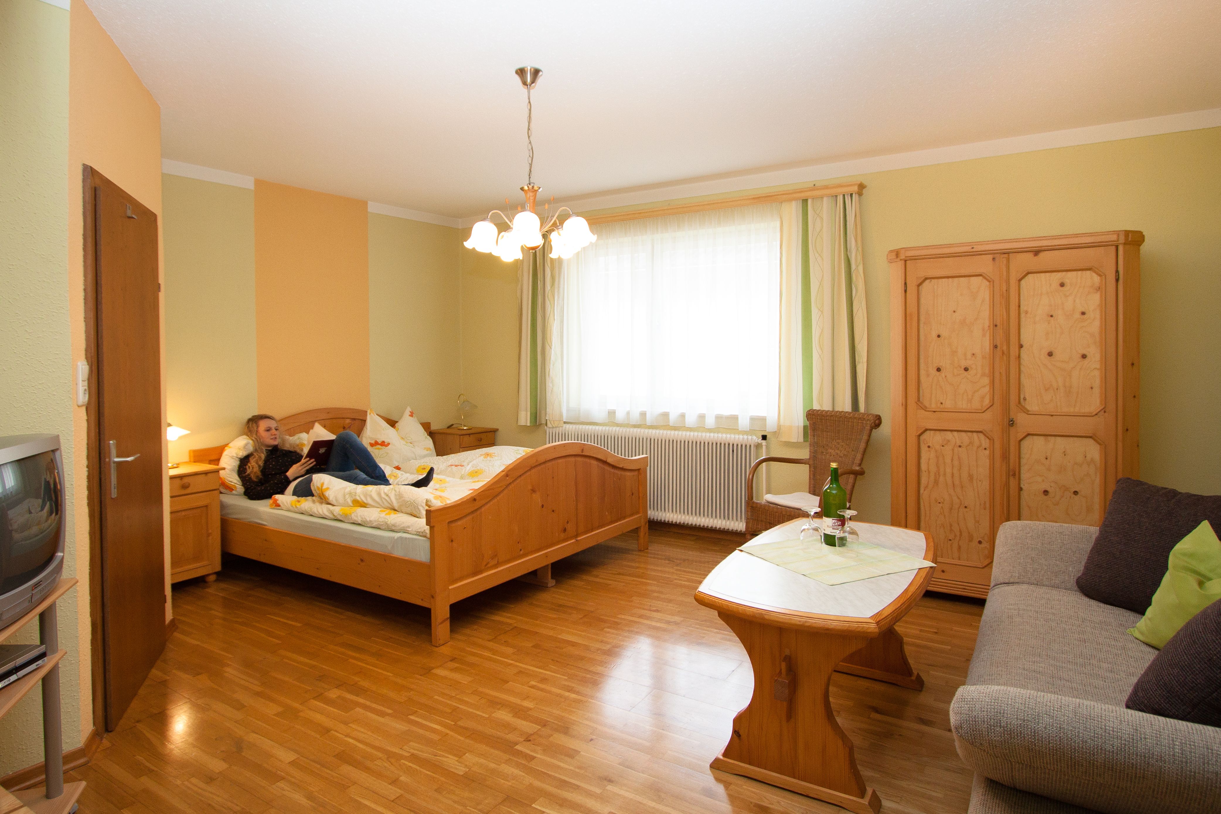 Útulný hotelový pokoj s dřevěným nábytkem, postelí, pohovkou a stolem.