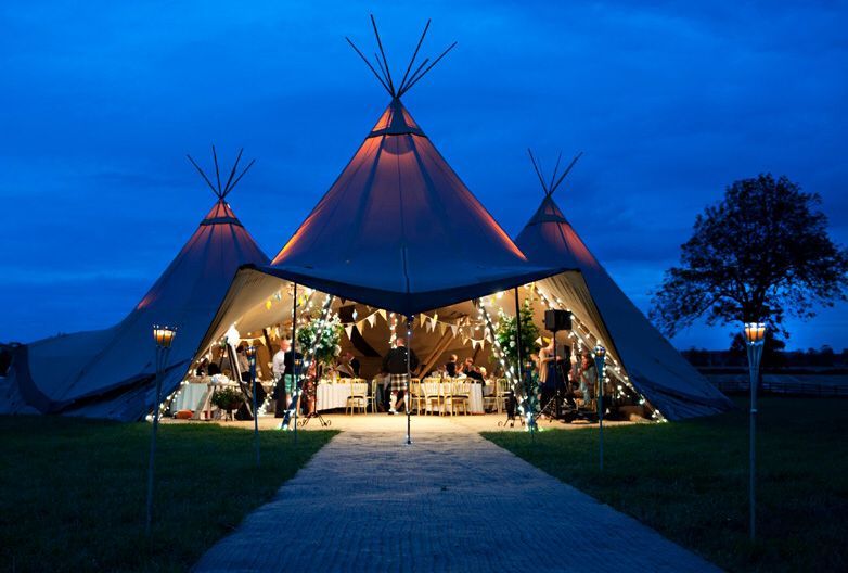 Osvětlený stan tipi v noci se slavnostní výzdobou a hosty uvnitř.