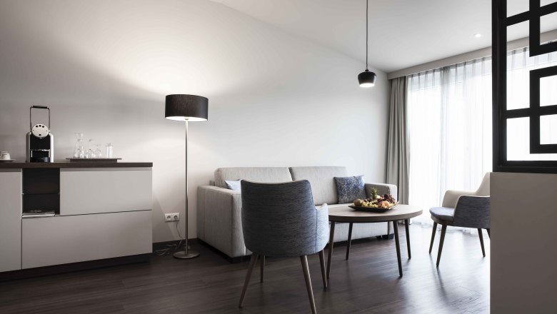 Modern&iacute; posezen&iacute; s pohovkou, křeslem, stolem a stojac&iacute; lampou ve světl&eacute; m&iacute;stnosti.