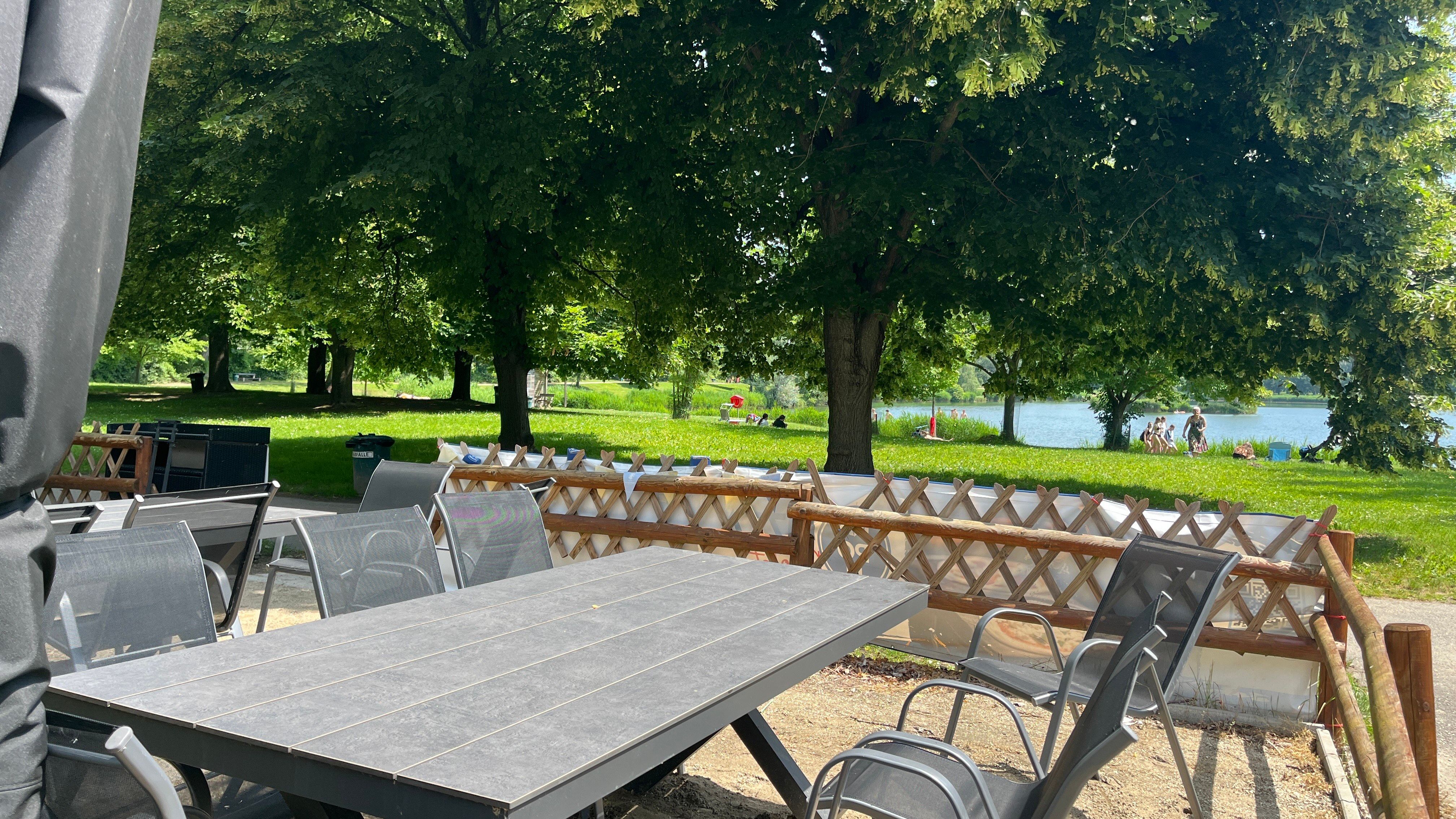 Zahradní stůl se zahradními židlemi, v pozadí bazén Tulln.