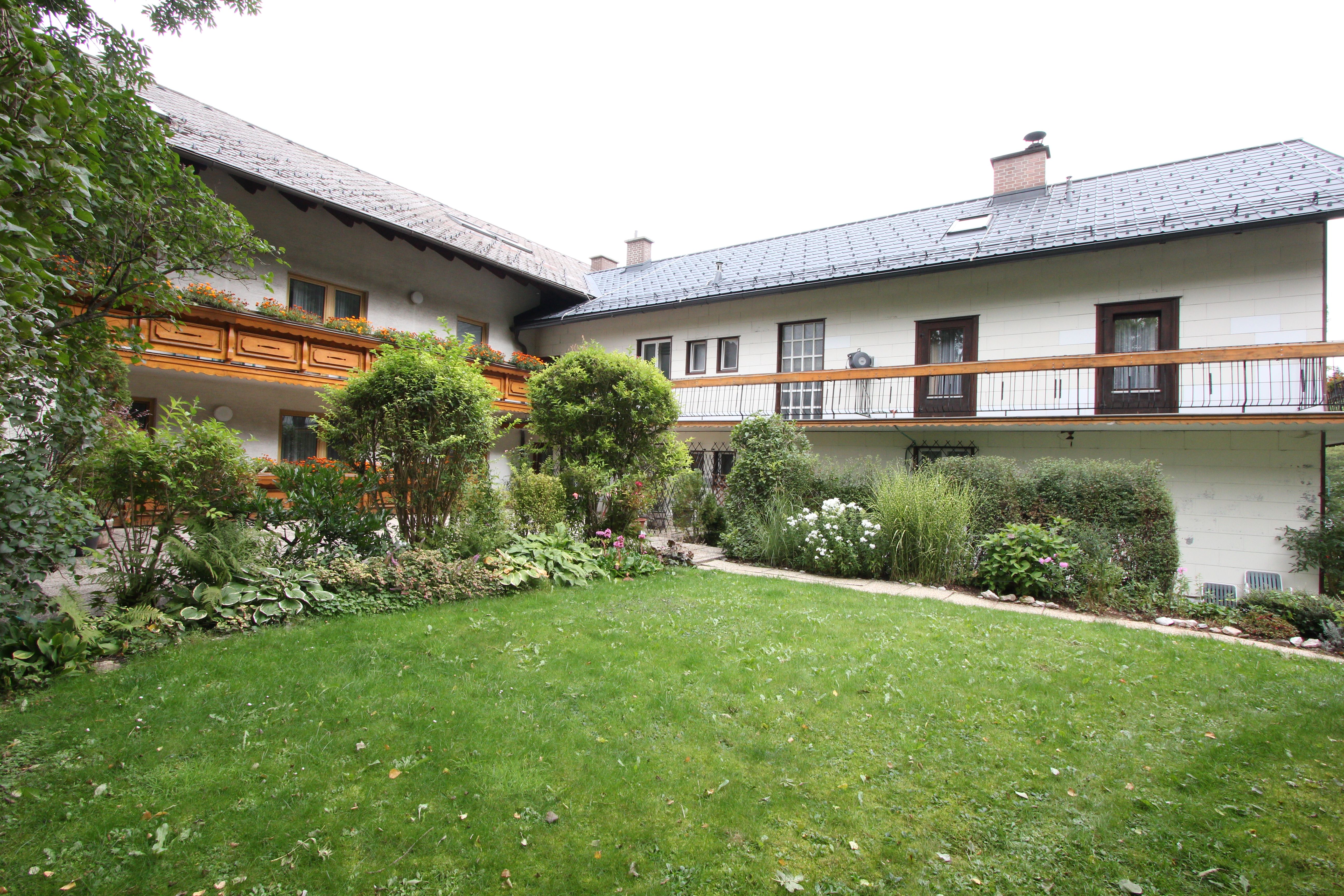 Tradiční dům s dřevěným balkonem a udržovanou zahradou.