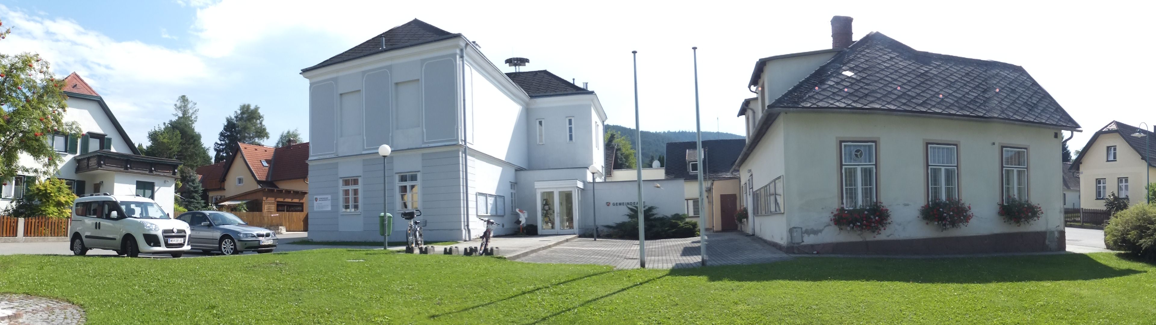 Panoramatický snímek obecního úřadu ve Waidmannsfeldu s okolními budovami a auty.