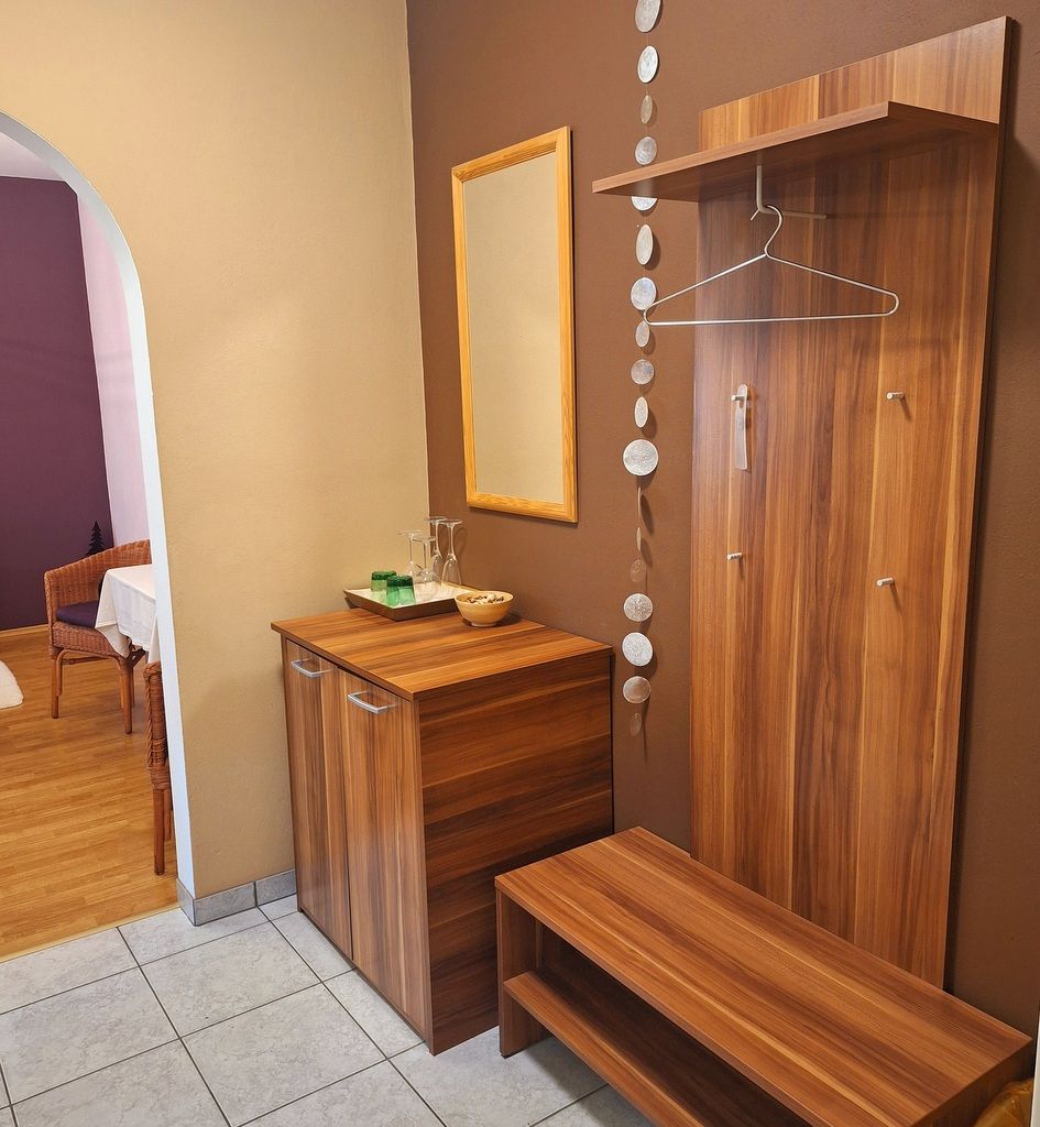 Moderní vstupní prostor s dřevěným nábytkem, zrcadlem a dekoracemi.