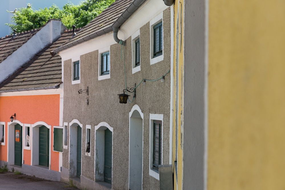 Barevné domky ve sklepních uličkách se zelenými dveřmi a okny.