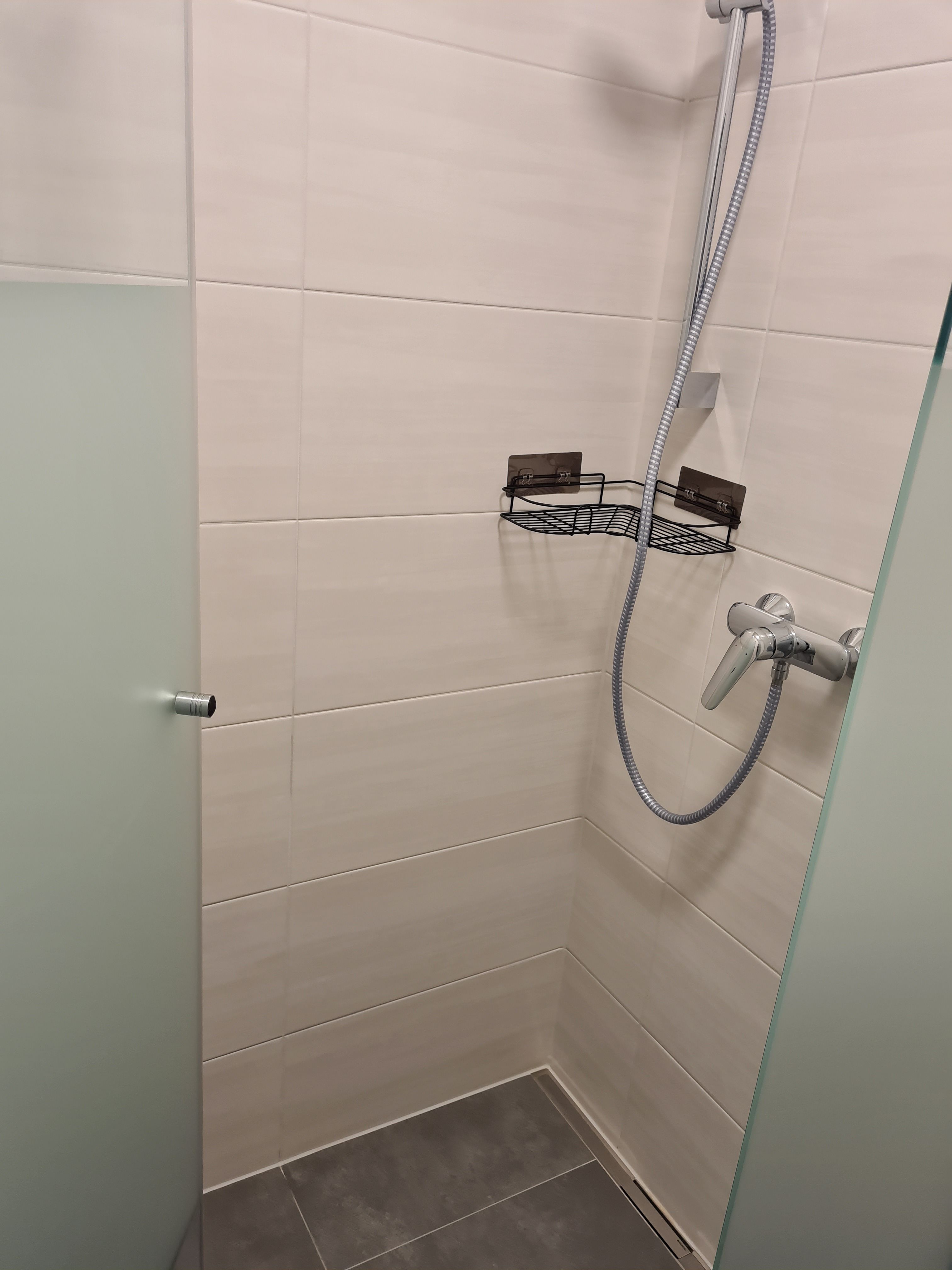 Moderní sprchový kout se skleněnou stěnou a sprchovou hlavicí.