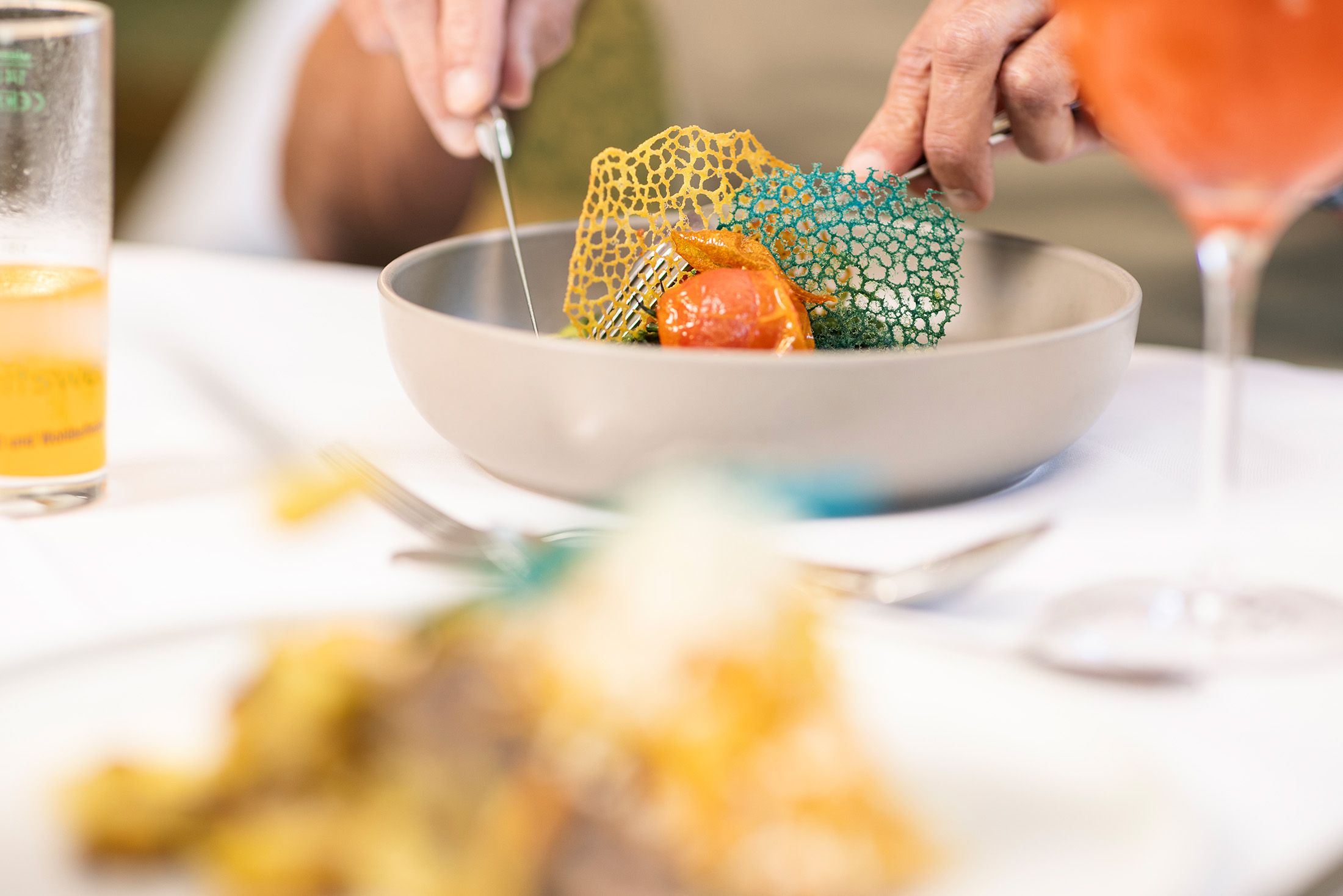 „V restauraci Kreuzberg je hostovi u prostřeného stolu servírováno čerstvě připravené jídlo. Na stole jsou nápoje a pokrmy. Světlá, příjemná atmosféra poskytuje náhled na návštěvu restaurace a osobní obsluhu.“