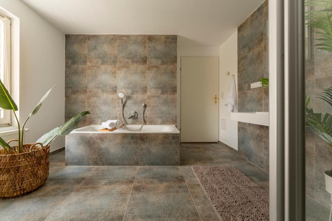 Moderní koupelna s vanou, rostlinami a ručníky.