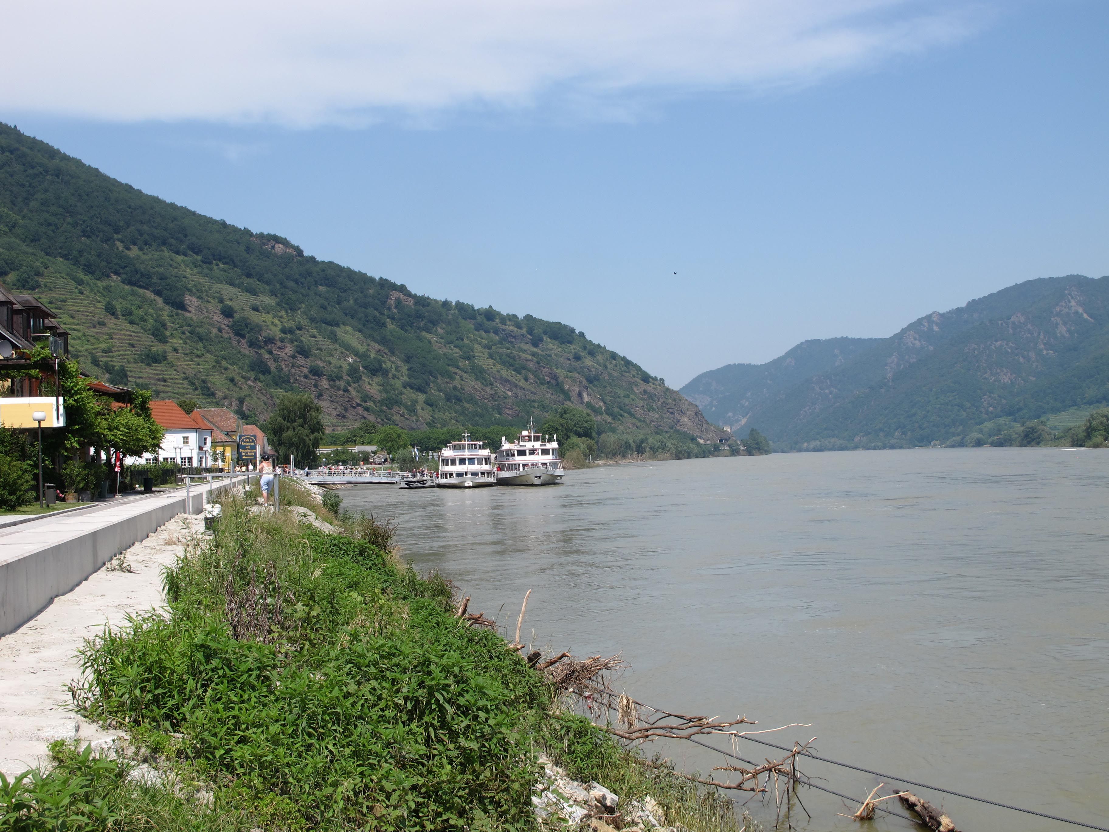 Přistávací plocha ve Špici na Dunaji s loděmi a kopci v pozadí.