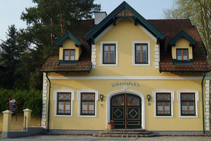 Žlutá budova s nápisem "Urbanistubn", obklopená stromy.