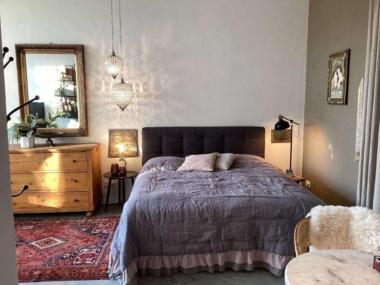 Útulná ložnice s manželskou postelí, dřevěným nábytkem a orientálním kobercem.