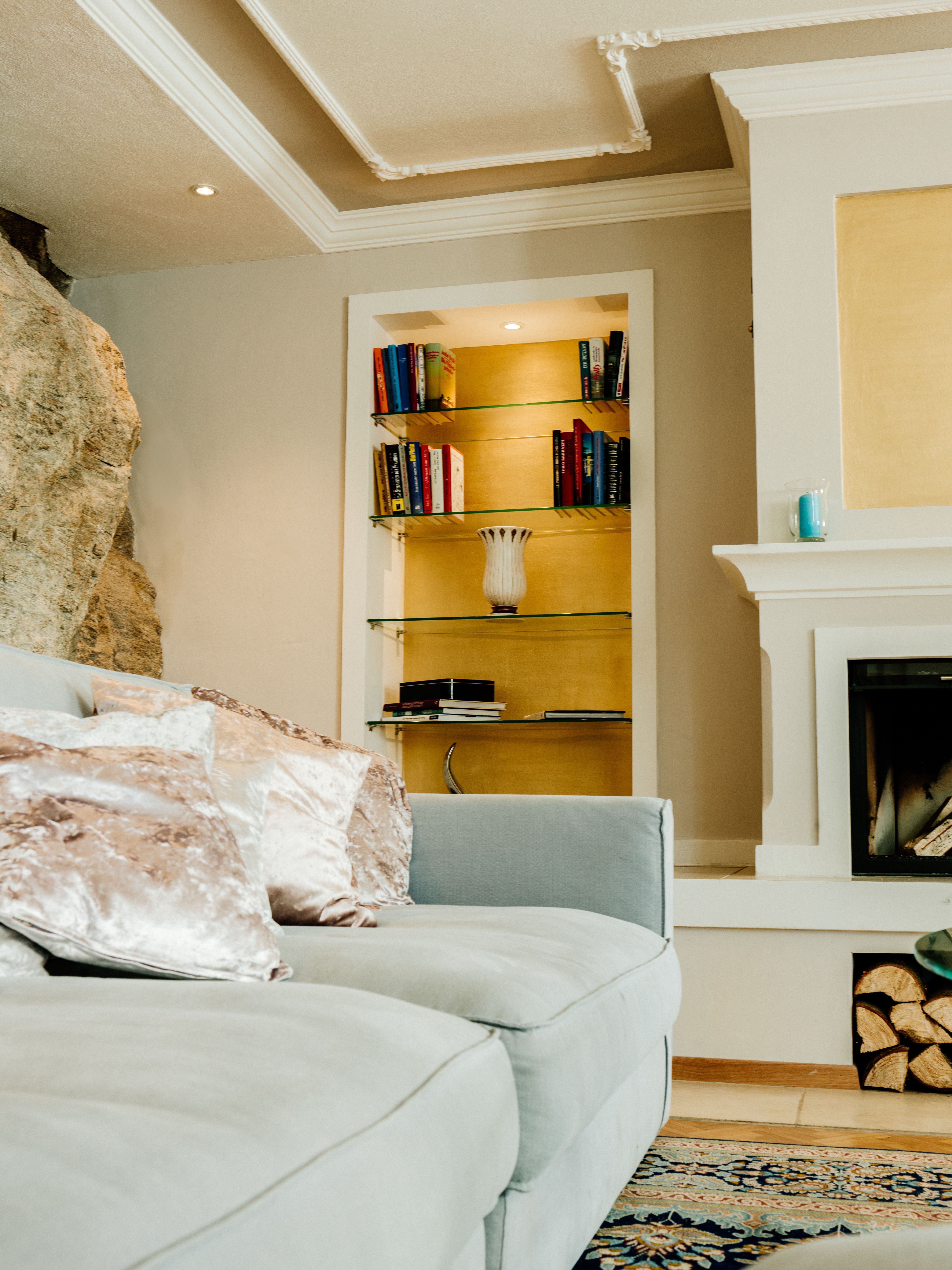 Elegantní obývací pokoj s šedou pohovkou, knihovnou a krbem.