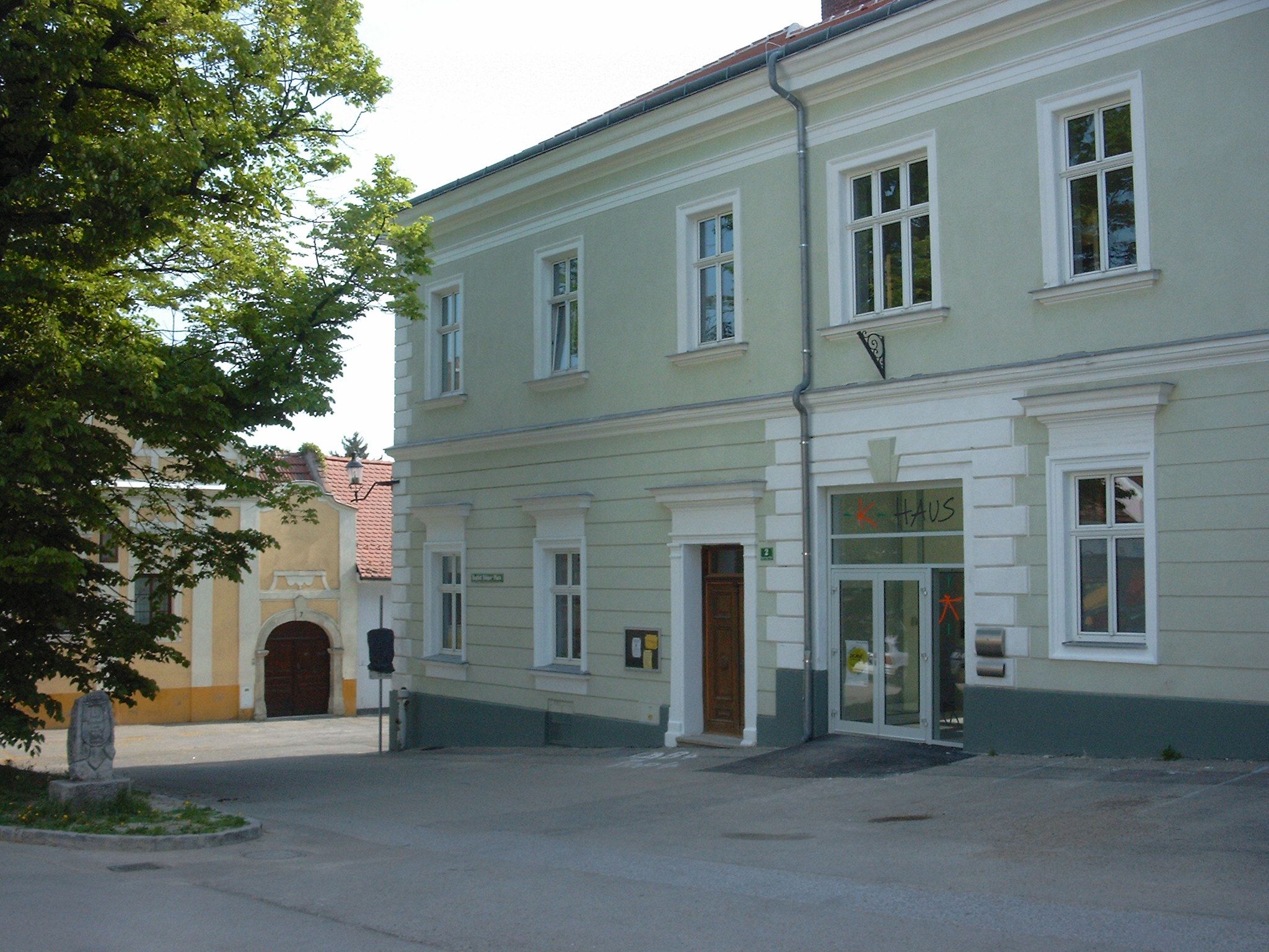 Dvoupodlažní světle zelená budova s nápisem "house" nad dveřmi.