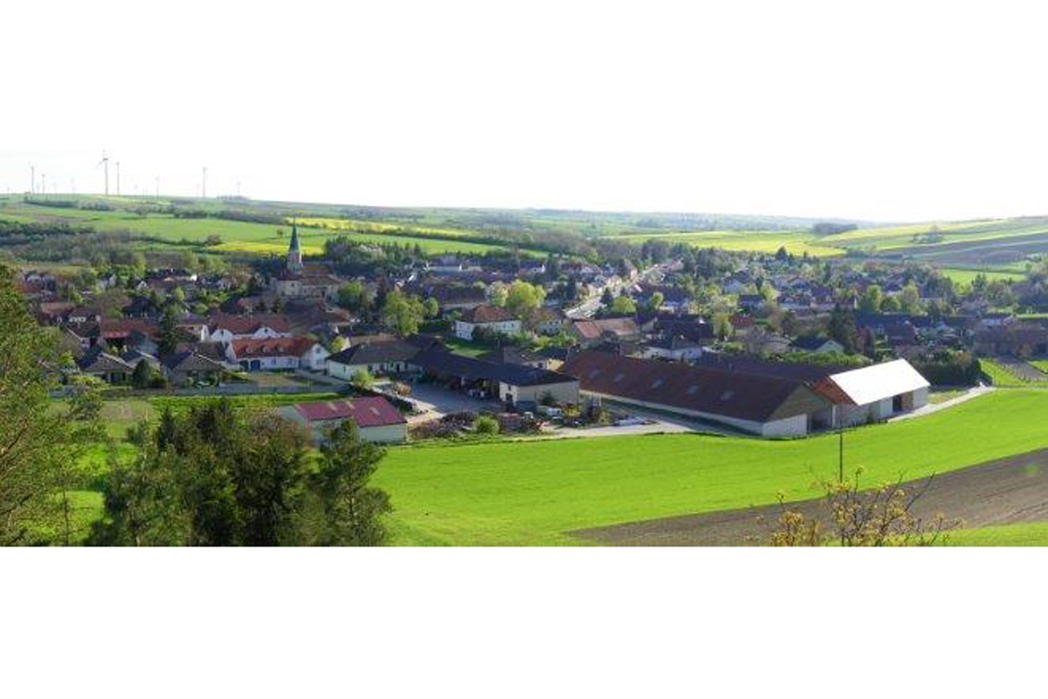 Krajina s vesnicí a kostelem, obklopená poli.