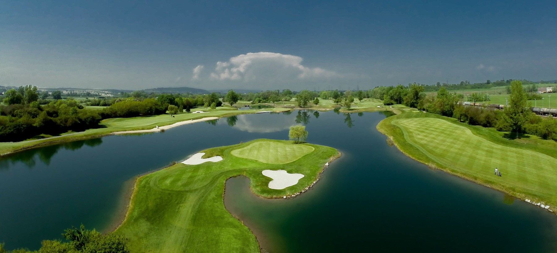Pohled na golfové hřiště s rozlehlým jezerem.