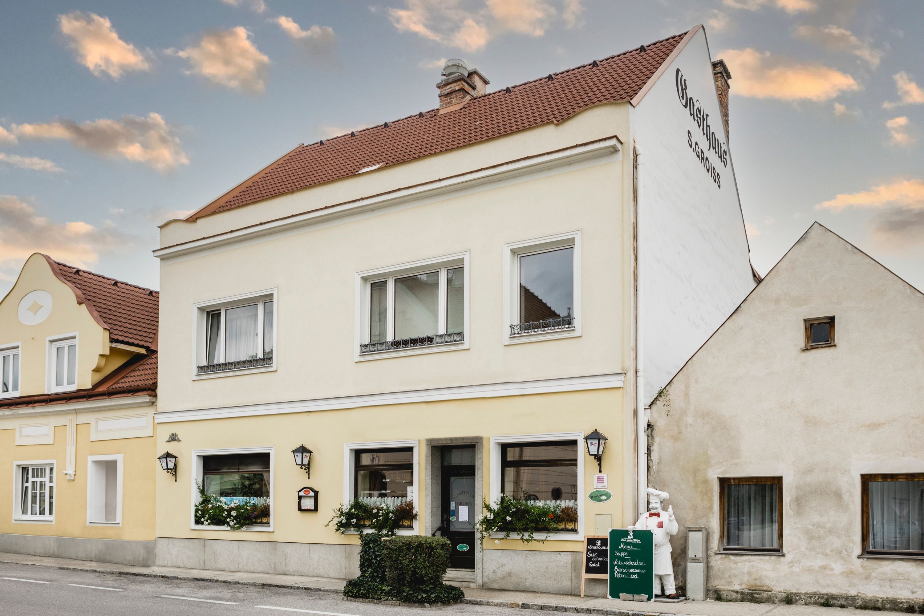 Žlutý hostinec s nápisy a květinami v Berndorfu.